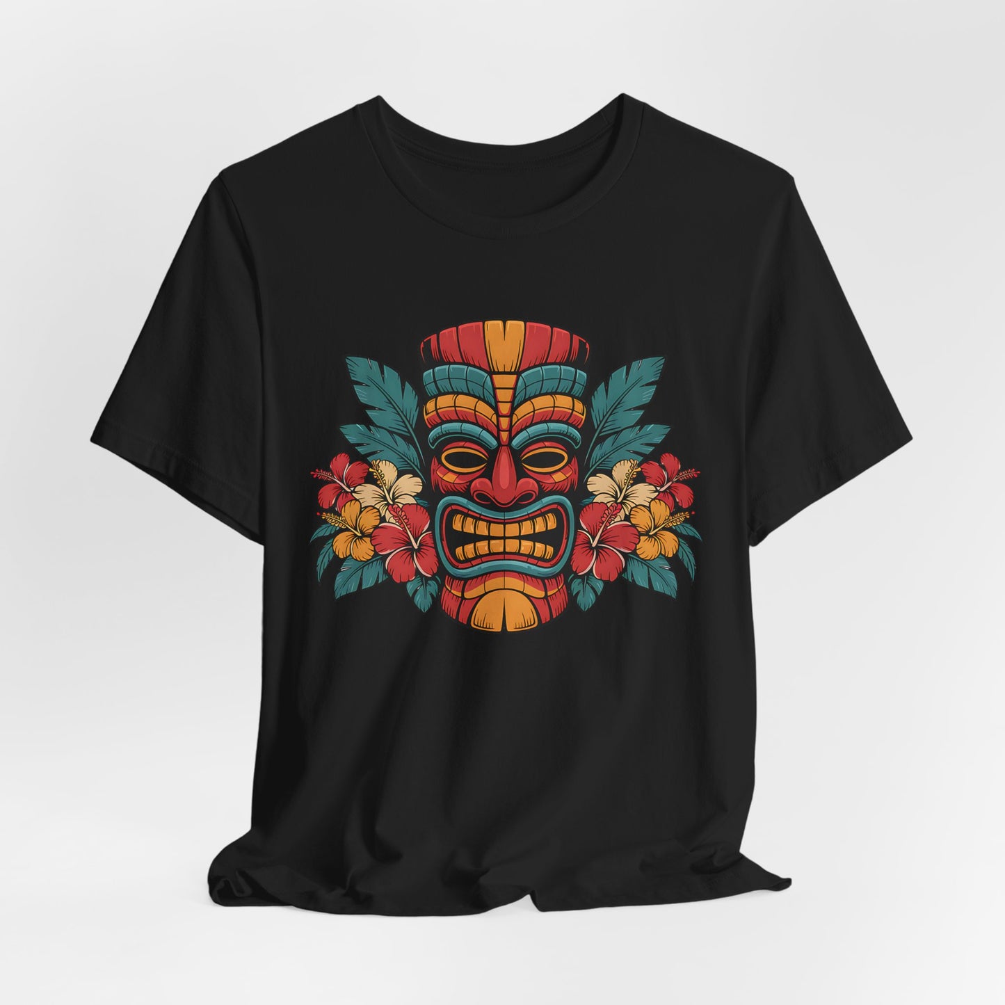 The Tropical Tiki Mask T-Shirt - Unisex Jersey Short Sleeve showcases a vibrant tiki mask in red, yellow, and orange with tropical flowers and green leaves—ideal for expressing a bold, tropical style.