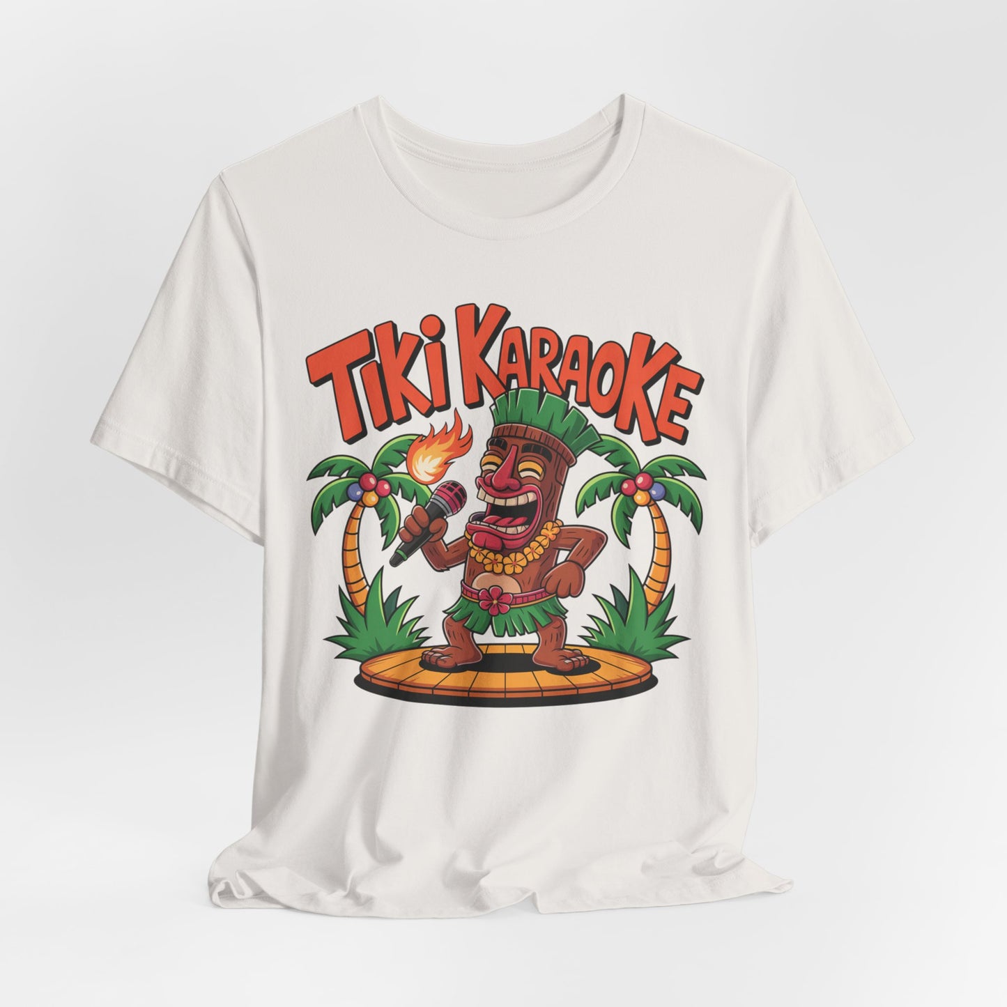 The Tiki Karaoke Unisex Short Sleeve Tiki T-Shirt showcases a vibrant cartoon Tiki with a torch on stage between palm trees, topped with bold red “Tiki Karaoke” text for a fun summer vibe.