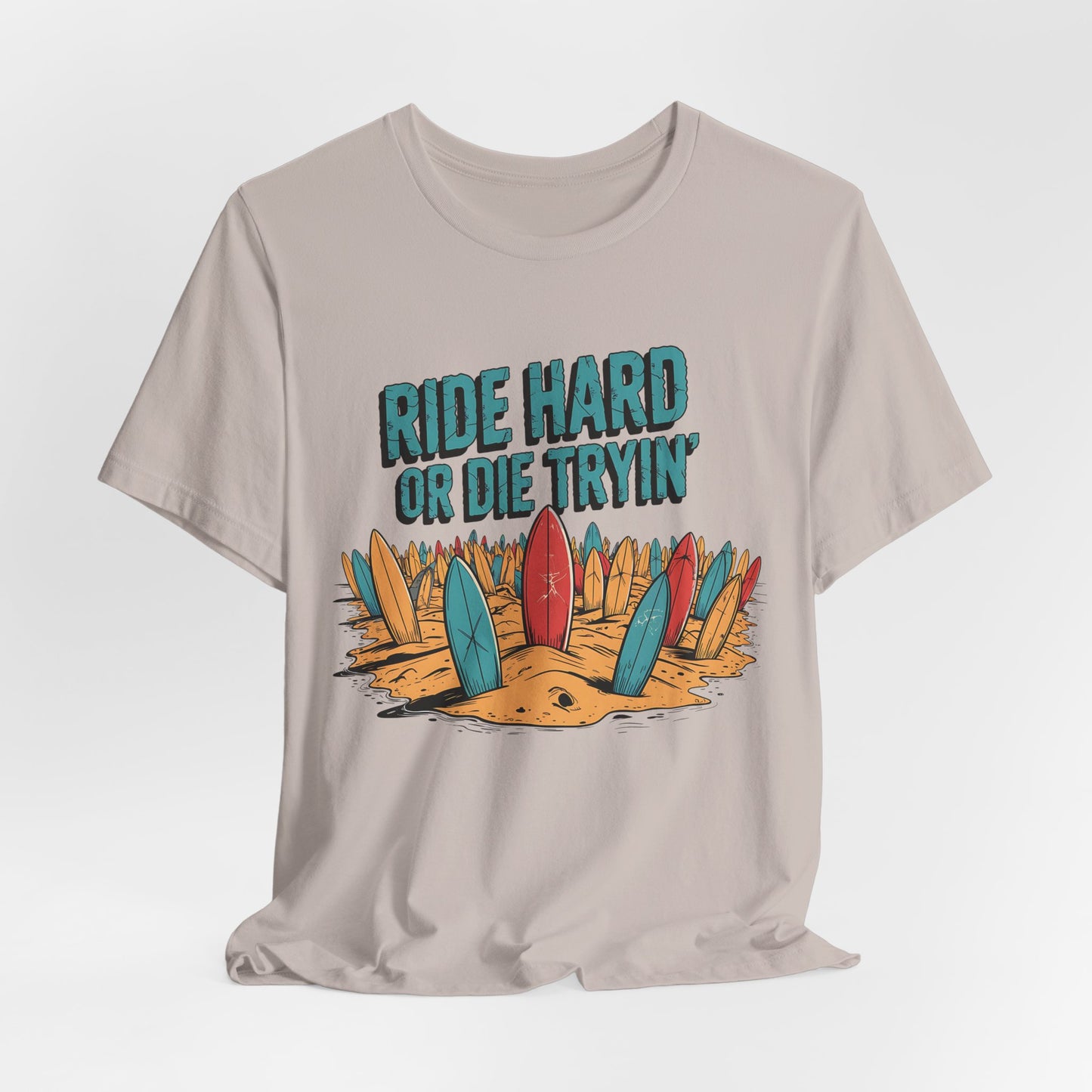 The Surfing T-Shirt - Ride Hard or Die Tryin is a beige unisex jersey tee with colorful surfboards in the sand and bold text—perfect for beach lovers who live the surf lifestyle.