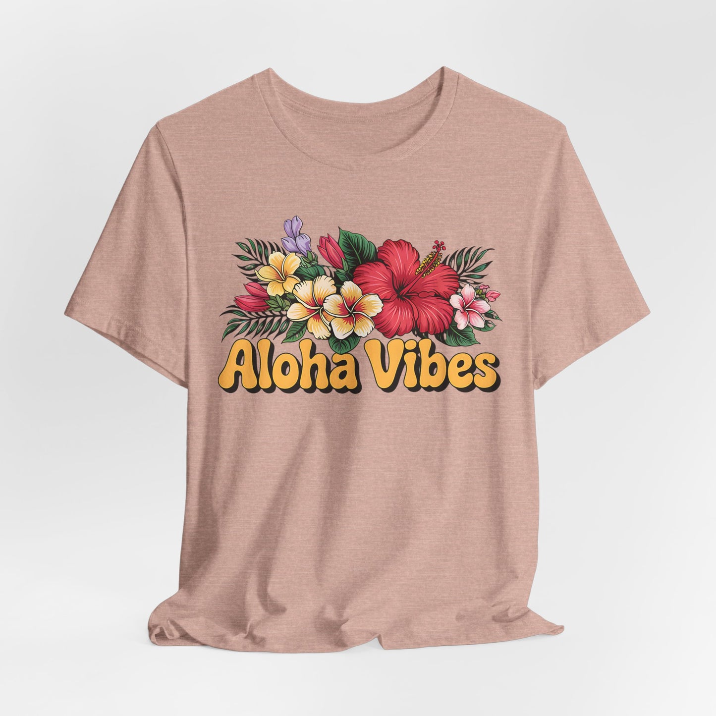 The Aloha Vibes Floral Unisex T-Shirt for Island Vibes features tropical flowers and green leaves with bold yellow “Aloha vibes” text on the front, made from breathable fabric and shown on a plain white background.