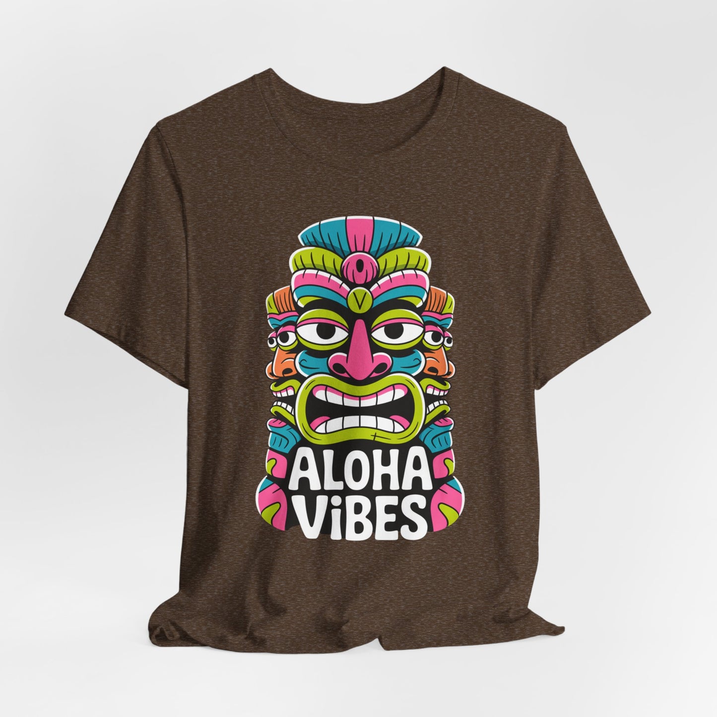 The Aloha Vibes Unisex Tiki T-Shirt features a vibrant tiki mask and bold white text in pink, green, blue, and yellow accents—perfect for bringing summer island energy to your style.