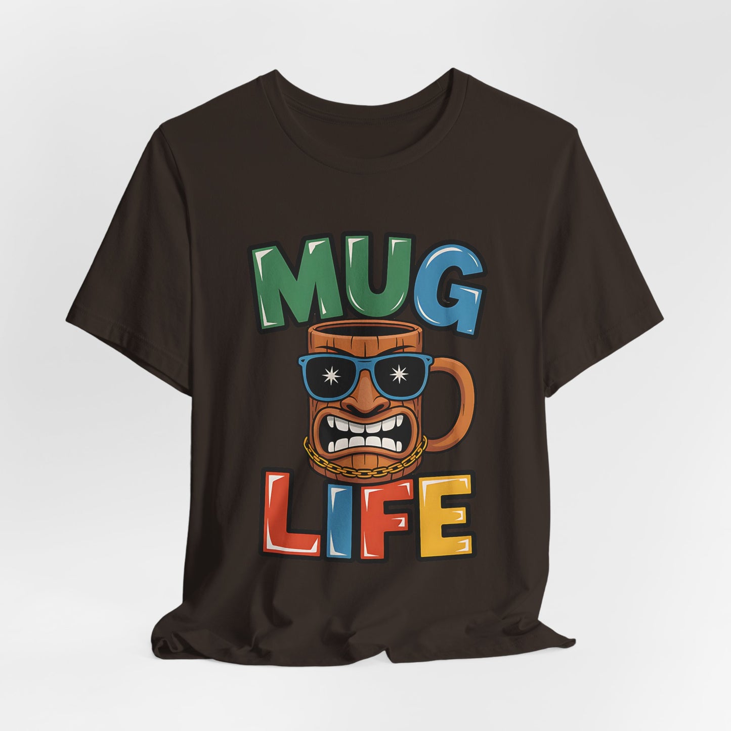The Mug Life Graphic Tiki T-Shirt is a fun unisex jersey tee for coffee lovers, featuring vibrant “MUG LIFE” text and a cartoon mug with sunglasses, gold chain, and attitude on a comfy short sleeve shirt.