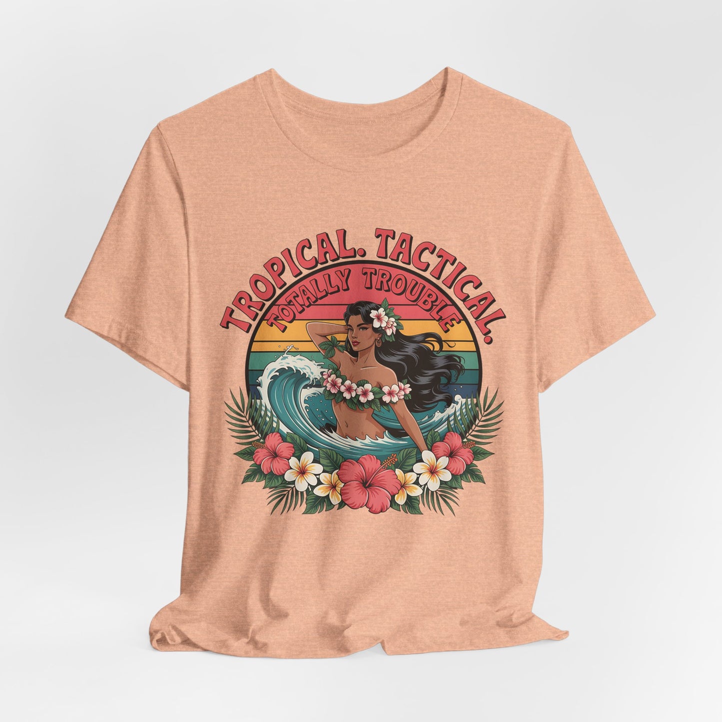 The Tropical Tactical Unisex Jersey T-Shirt - Aloha Vibes & Summer Fun in peach features a vibrant hula dancer print with flowers and a sunset, soft Airlume cotton, and “TROPICAL TACTICAL TOTALLY TROUBLE” text.