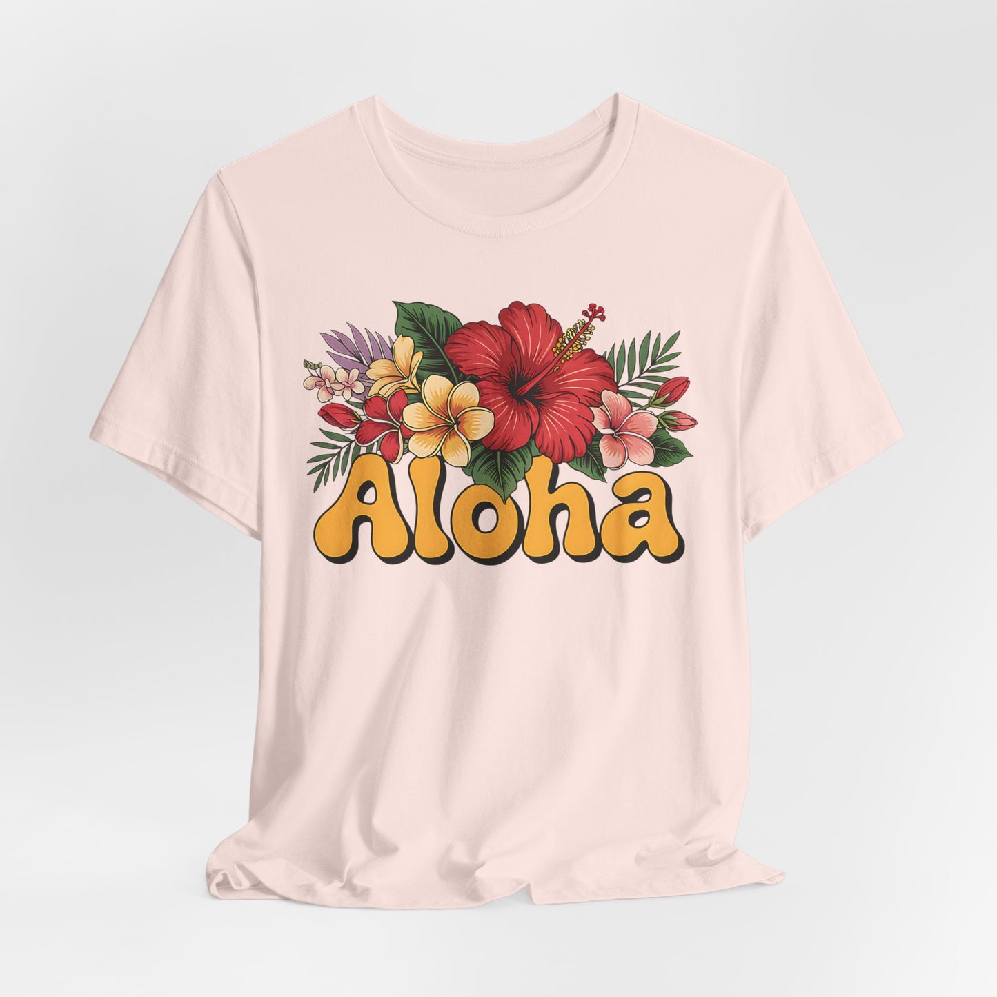 The Aloha Floral Unisex Jersey T-Shirt - Tropical Vibes, Casual Summer Style features a colorful hibiscus and plumeria design above bold yellow Aloha retro lettering on soft light pink Airlume cotton.