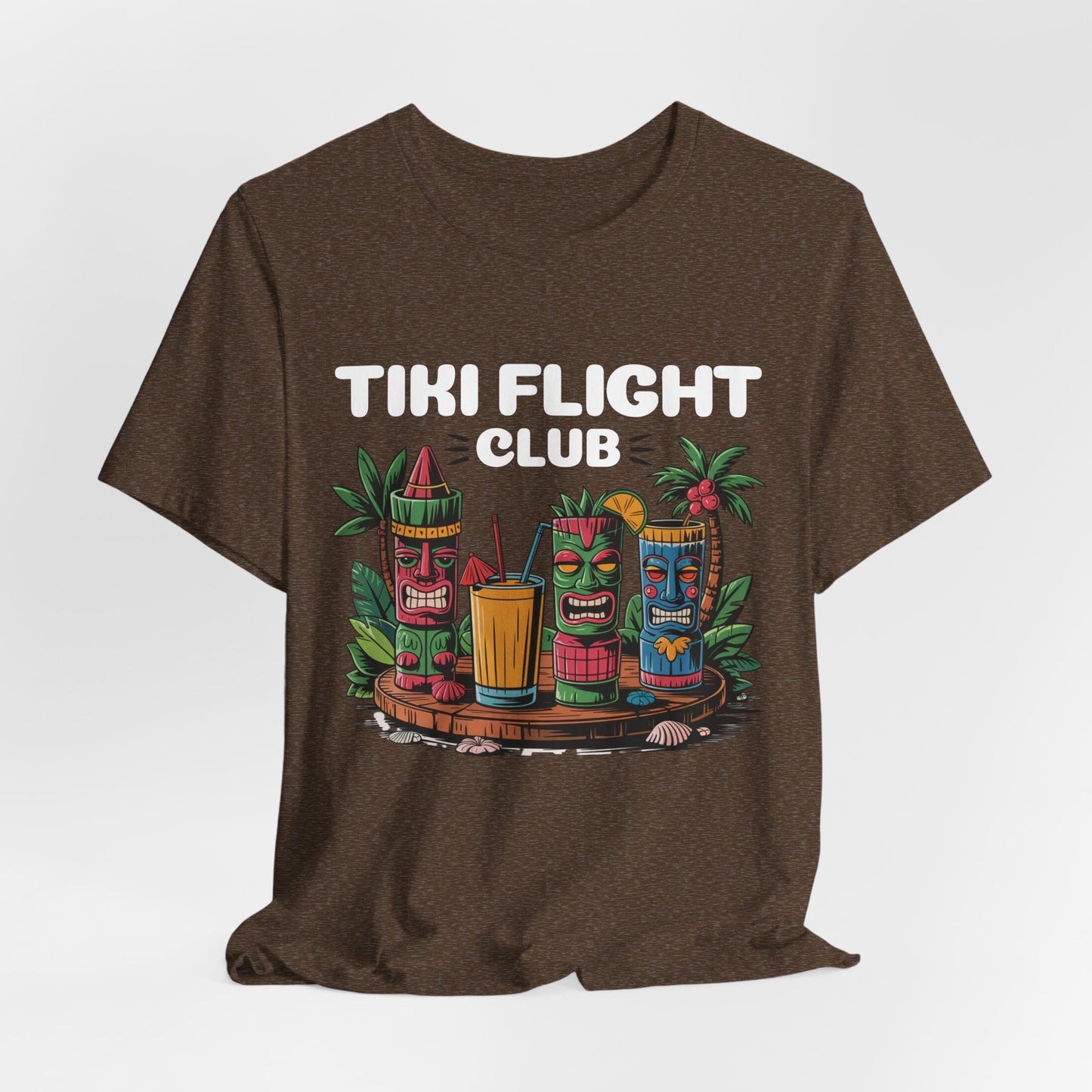 The Tiki Flight Club Graphic Tiki T-Shirt is a unisex summer vibe tee featuring colorful tiki faces, tropical drinks, green leaves, and bold TIKI FLIGHT CLUB text—a perfect casual choice for any beach day.