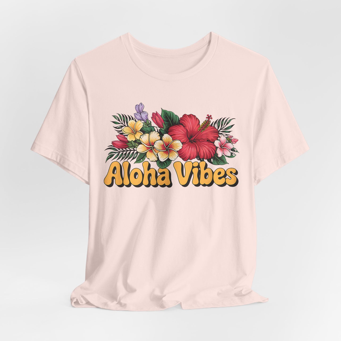 The Aloha Vibes Floral Unisex T-Shirt for Island Vibes features a light pink color, tropical flower graphics, bold yellow Aloha Vibes text, and is made from soft Airlume combed and ring-spun cotton for superior comfort.