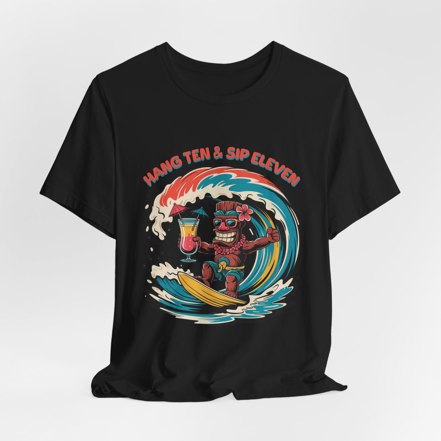 The Surf Vibe Tiki T-Shirt - Hang Ten & Sip Eleven Unisex Jersey Short Sleeve features a black, surf-inspired cartoon tiki surfing with drinks and the phrase above. Made from breathable cotton for all-day comfort.