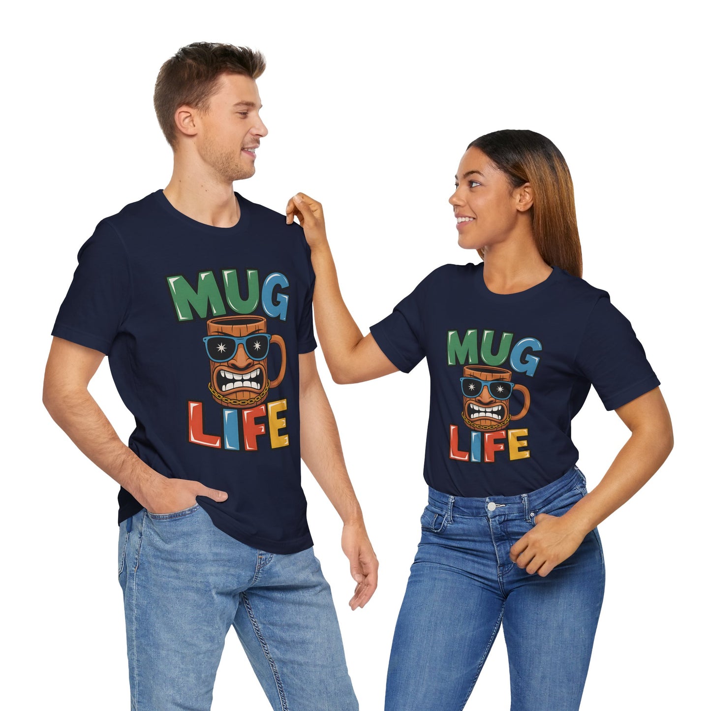 A smiling man and woman, both coffee lovers, wear matching “Mug Life Graphic Tiki T-Shirt - Fun Unisex Jersey Short Sleeve T-Shirts” with a cartoon mug. In blue jeans, they face each other as the woman touches the mans shoulder.