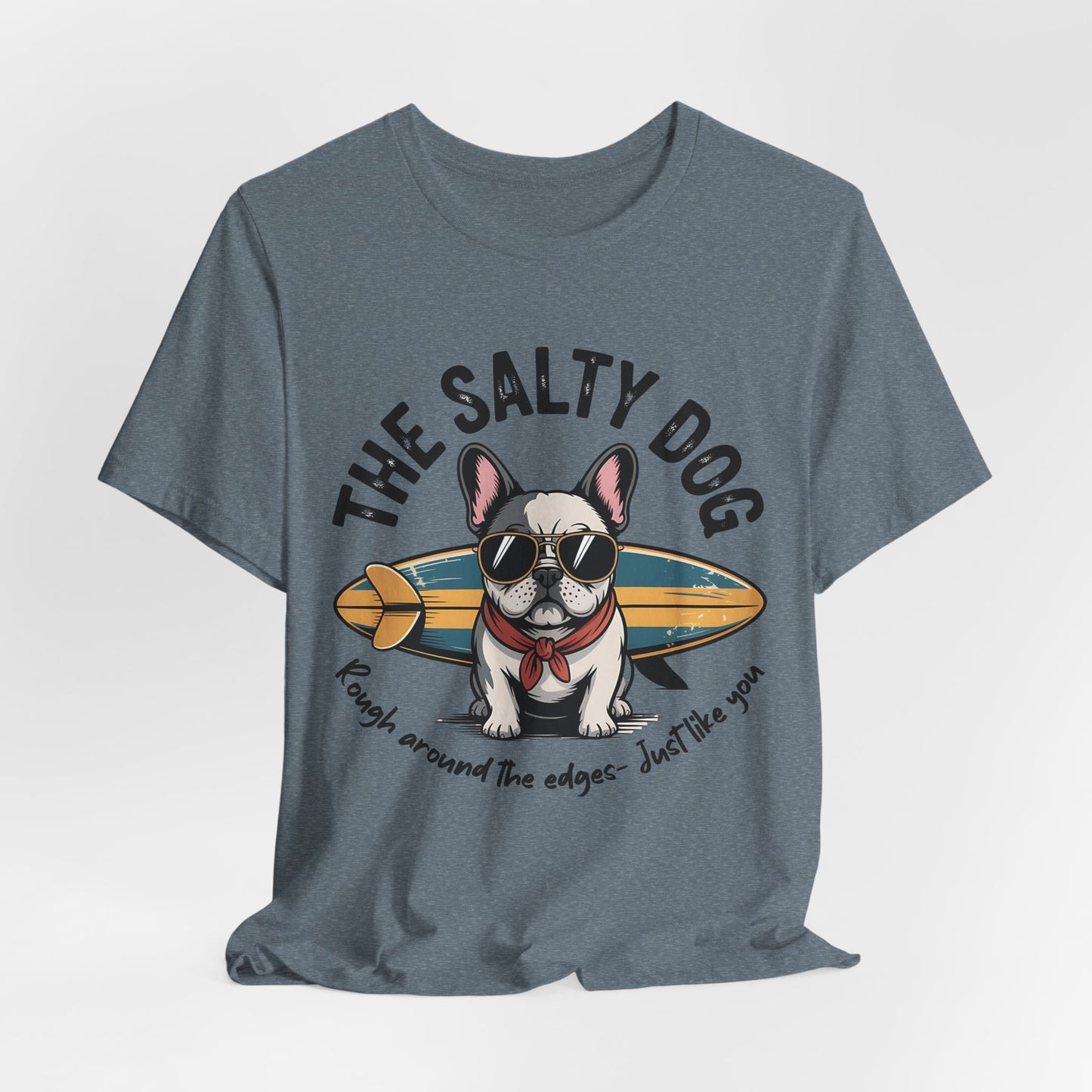 The Salty Dog Unisex Surf T-Shirt is a blue tee with a French Bulldog in sunglasses and a red bandana by a surfboard. It reads THE SALTY DOG and Rough around the edges – just like you. Perfect for beach lovers.