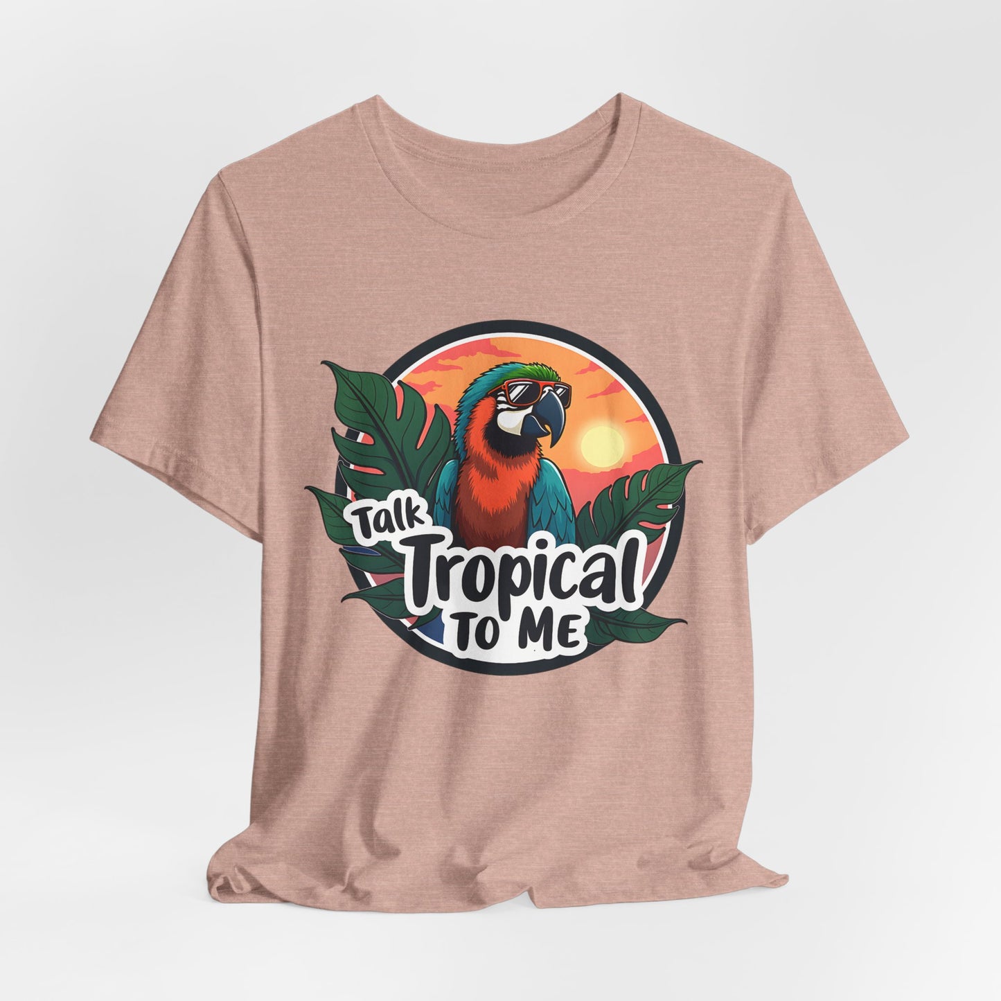 The Tropical Parrot Tee - Talk Tropical to Me Unisex Jersey Short Sleeve Shirt features a vibrant parrot in sunglasses with tropical leaves and a sunset, plus the playful phrase Talk Tropical To Me printed below.