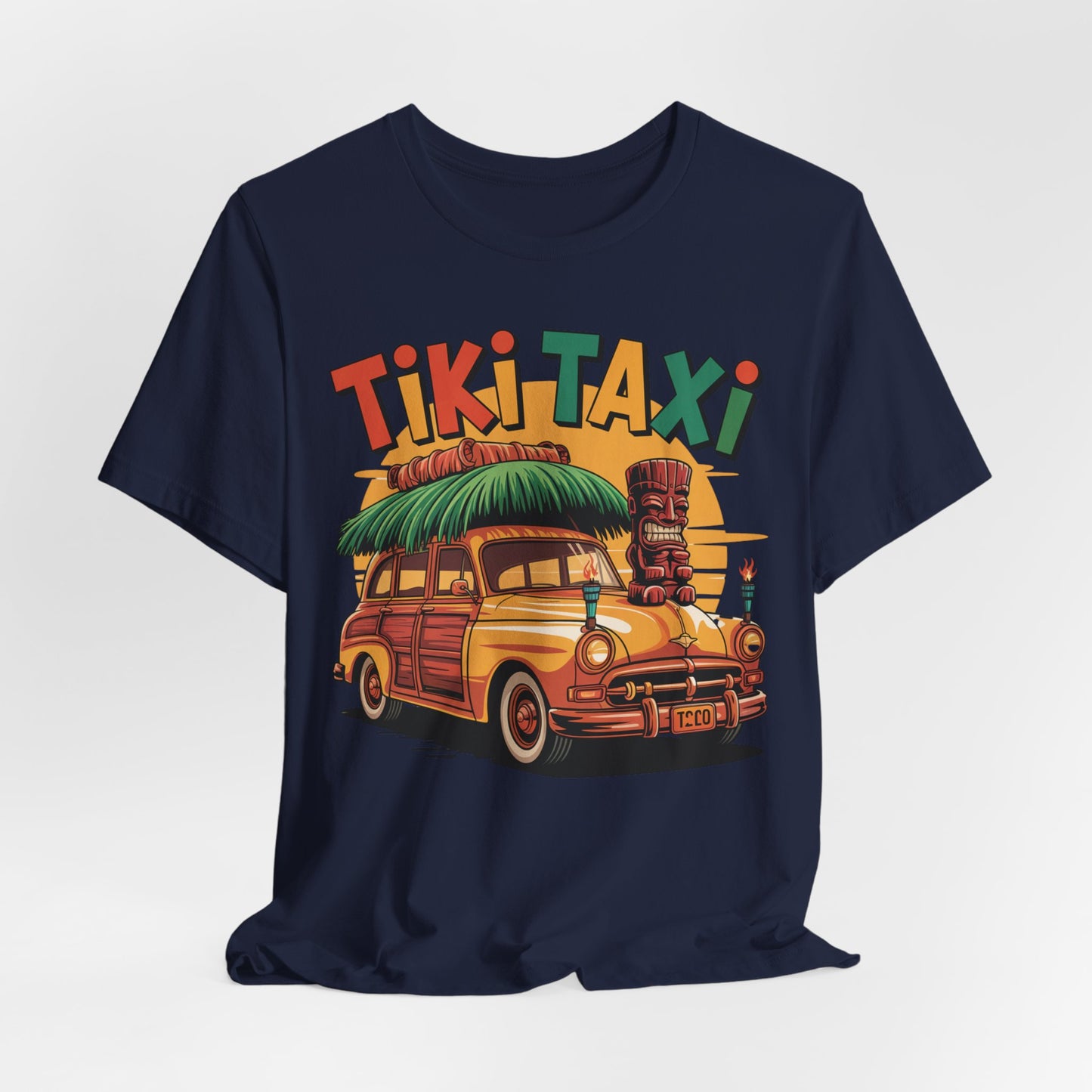 The Tiki Taxi Graphic Tiki T-Shirt for Summer Vibes in navy blue features a vibrant vintage woodie car, tiki statue, surfboard, and palm leaves with bold Tiki Taxi text—ideal for beach lovers seeking tropical flair.