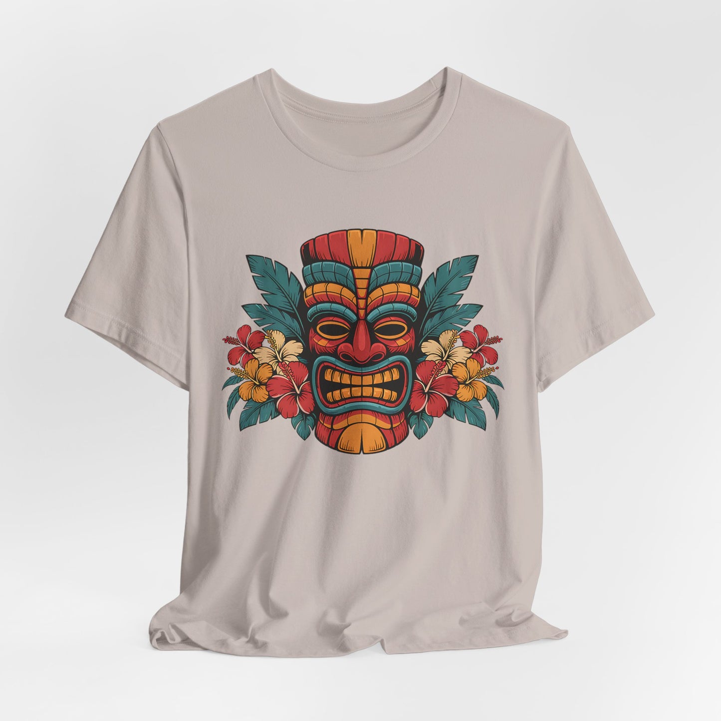 The Tropical Tiki Mask T-Shirt - Unisex Jersey Short Sleeve features a vibrant Tiki mask with hibiscus flowers and green leaves. Crafted from breathable fabric, it offers all-day comfort and a true tropical vibe.