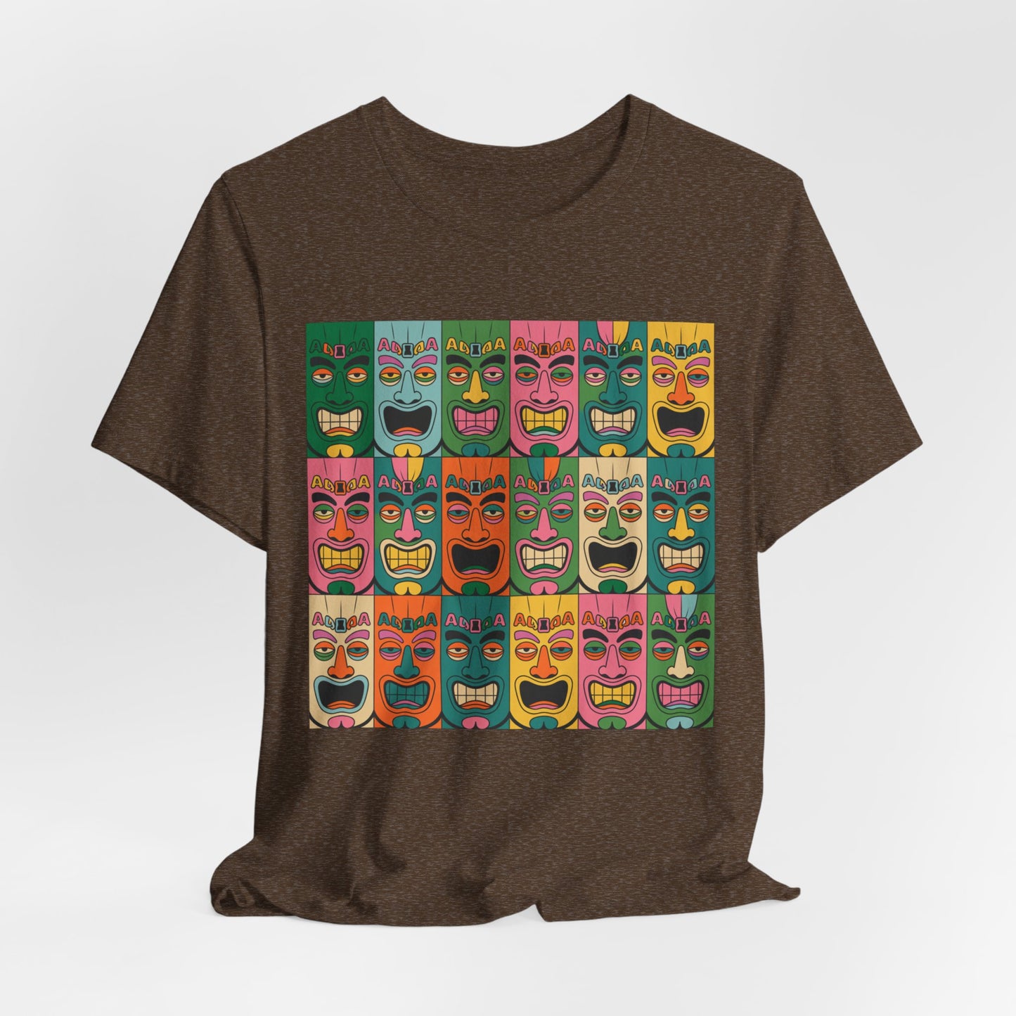 The Vibrant Tribal Mask Unisex Tiki T-Shirt in brown features cartoonish tiki faces with bold expressions on colorful backgrounds, crafted through eco-friendly manufacturing.