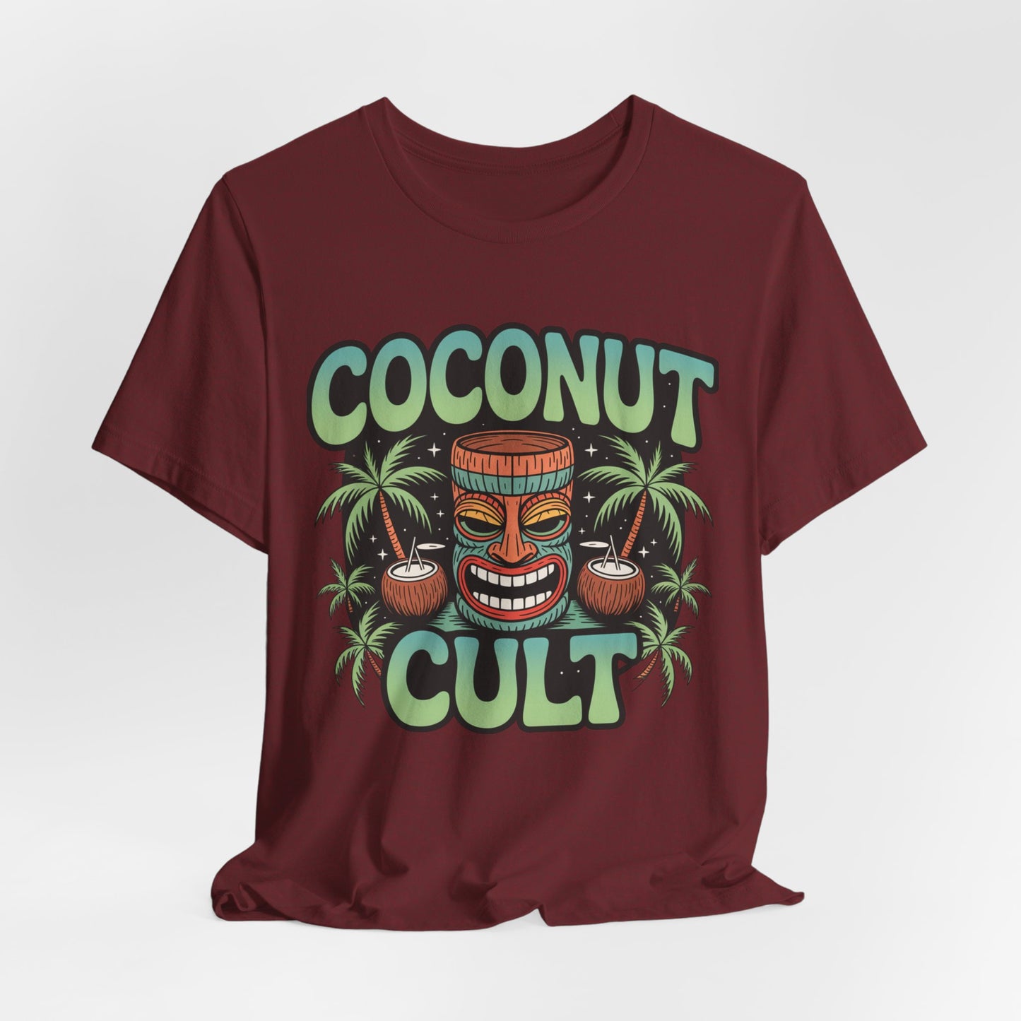 The Coconut Cult Unisex Jersey Tiki T-Shirt features bold green COCONUT CULT text, a tiki face, coconuts, and palm trees on maroon Airlume Cotton—ideal for beach lovers seeking tropical vibes.