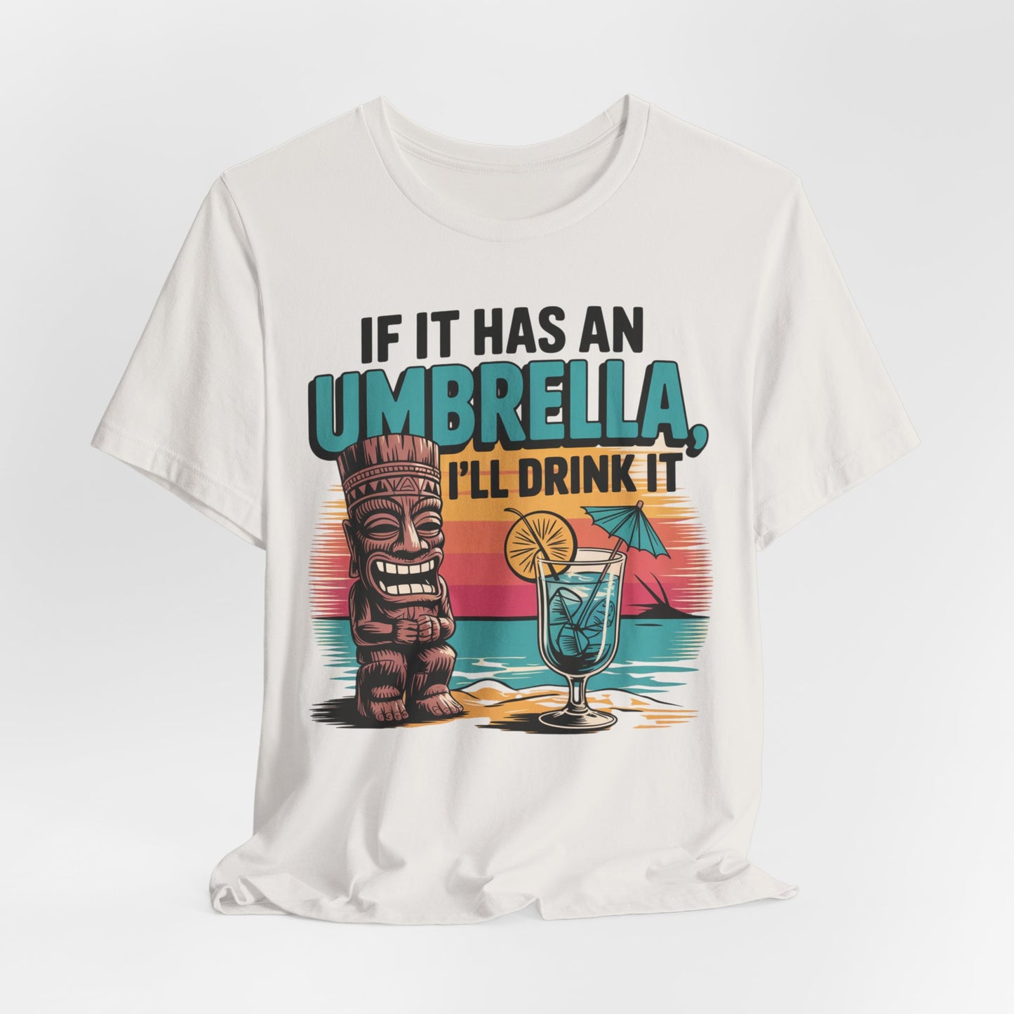 The Tropical Fun Tiki T-Shirt features a vibrant beach design with a tiki statue, cocktail, and bold If It Has an Umbrella, Ill Drink It text—perfect for anyone who loves tropical vibes.