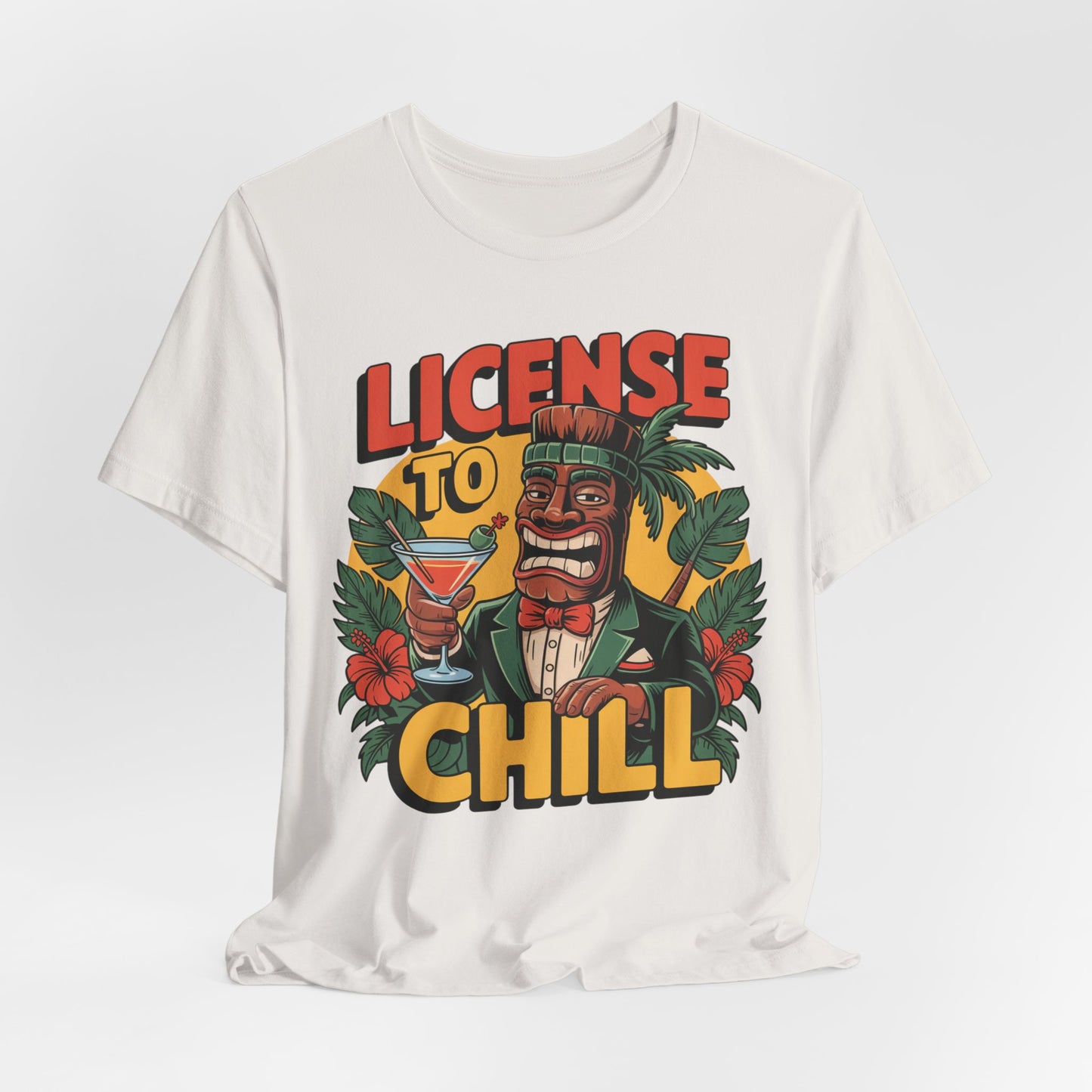 The T-Shirt - License to Chill Tropical Graphic Tiki T-Shirt features a cartoon tiki in a suit with a cocktail, tropical leaves and flowers, and bold “LICENSE TO CHILL” text. A fun unisex tee—perfect for summer barbecues!.