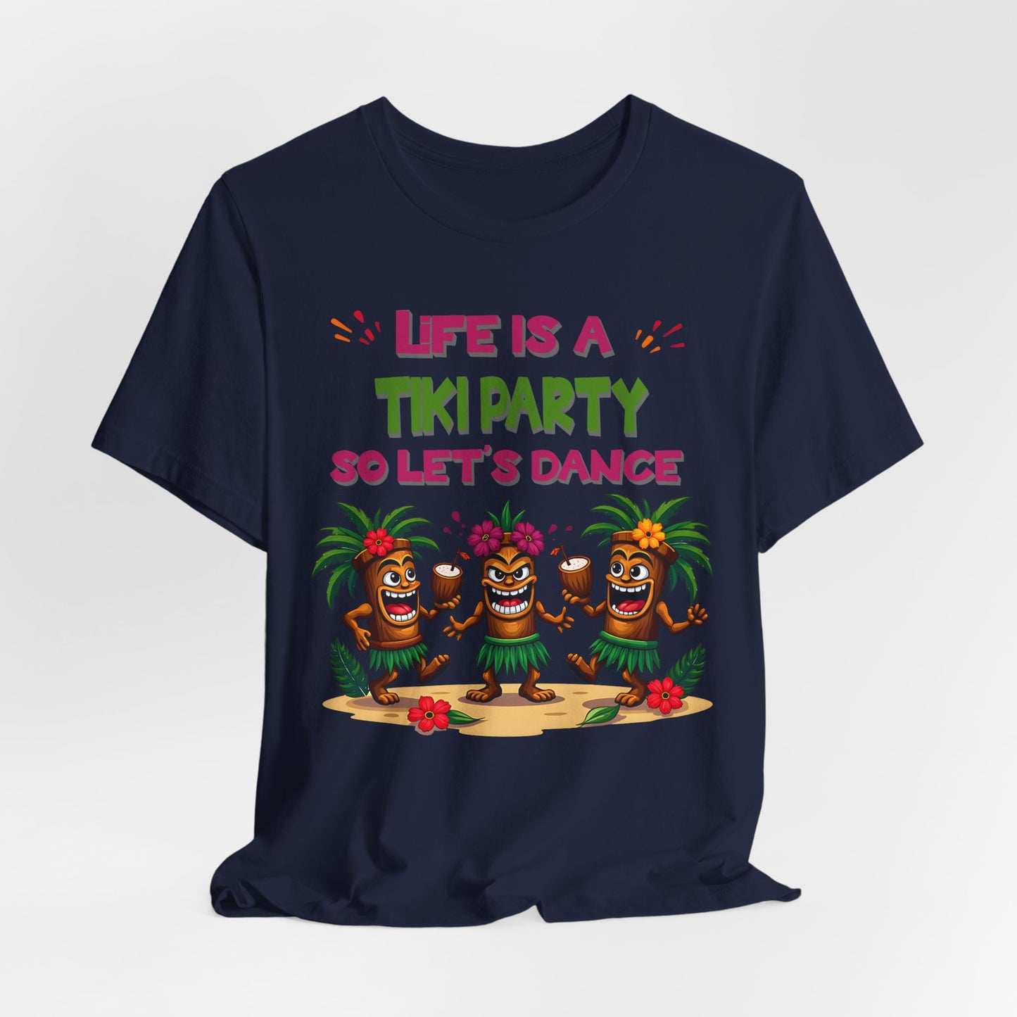 The Tiki Party T-Shirt features three cartoon tiki figures dancing on sand with tropical flowers and the phrase “Life is a Tiki Party so Let’s Dance” in colorful letters—perfect for summer fun!.