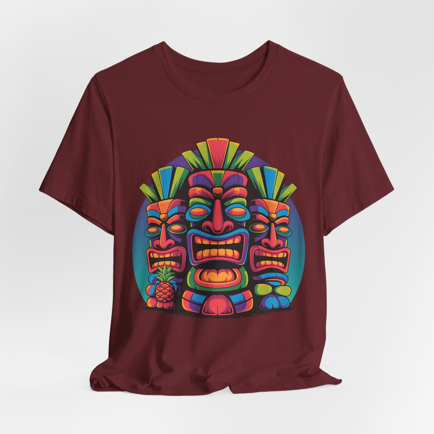 The Vibrant Tribal Mask Tiki T-Shirt - Unisex Short Sleeve features a maroon tee with three colorful, stylized tribal masks in bold geometric patterns on a circular background—a unique and eye-catching addition to any casual wardrobe.