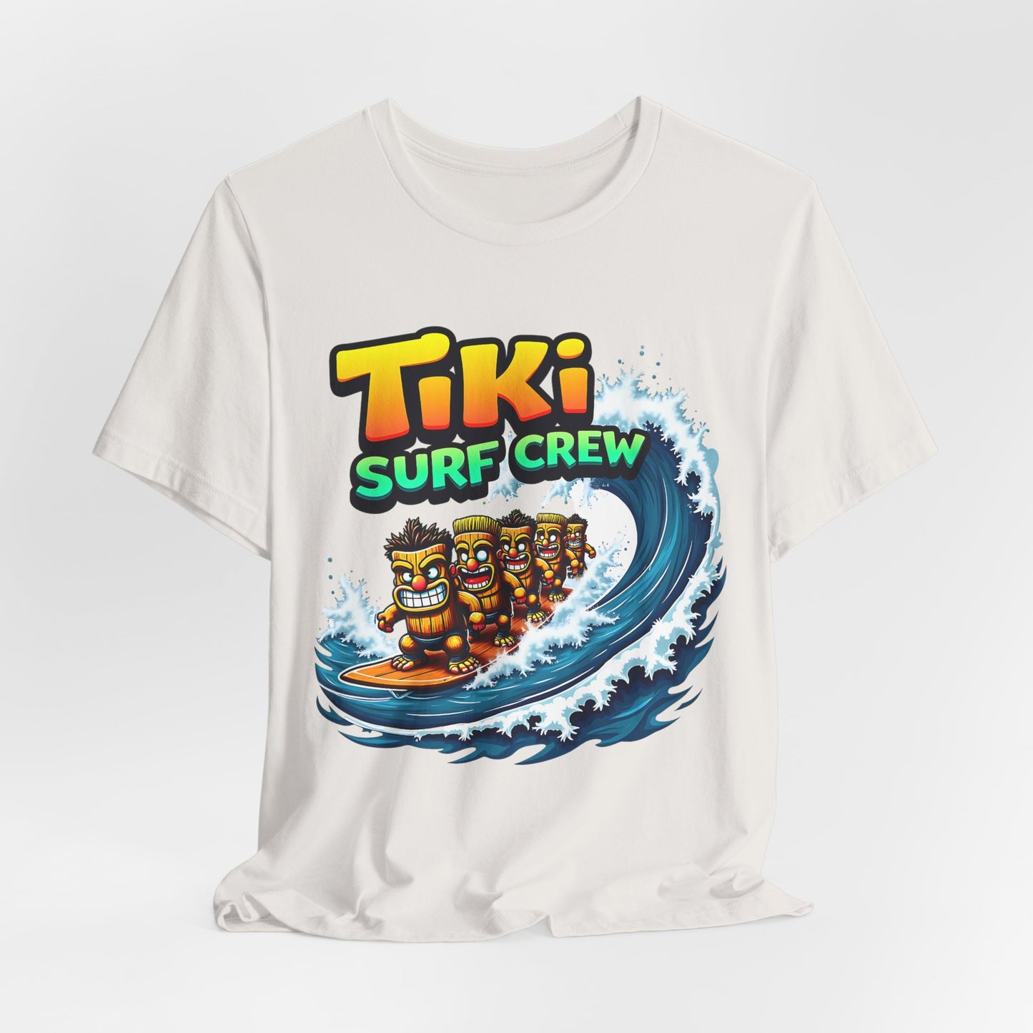 The Tiki Surf Crew Graphic Tiki T-Shirt is a fun unisex jersey short sleeve shirt for surf lovers, showcasing four cartoon tikis surfing a blue wave with Tiki Surf Crew above—ideal for beach and surf culture fans.