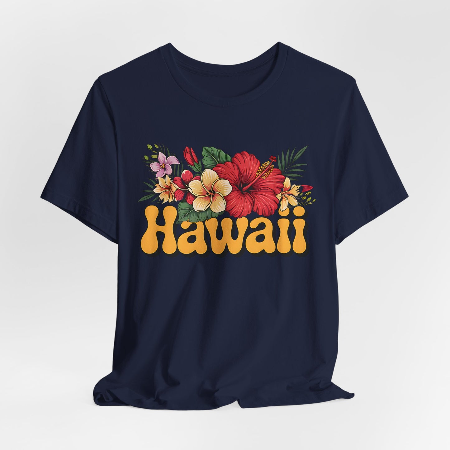 The Hawaiian Floral Unisex Tee - Beach Vibes and Island Spirit features Hawaii in bold yellow retro letters with a vibrant hibiscus, plumeria, and green leaves design on navy blue, made from ultra-soft Airlume cotton.