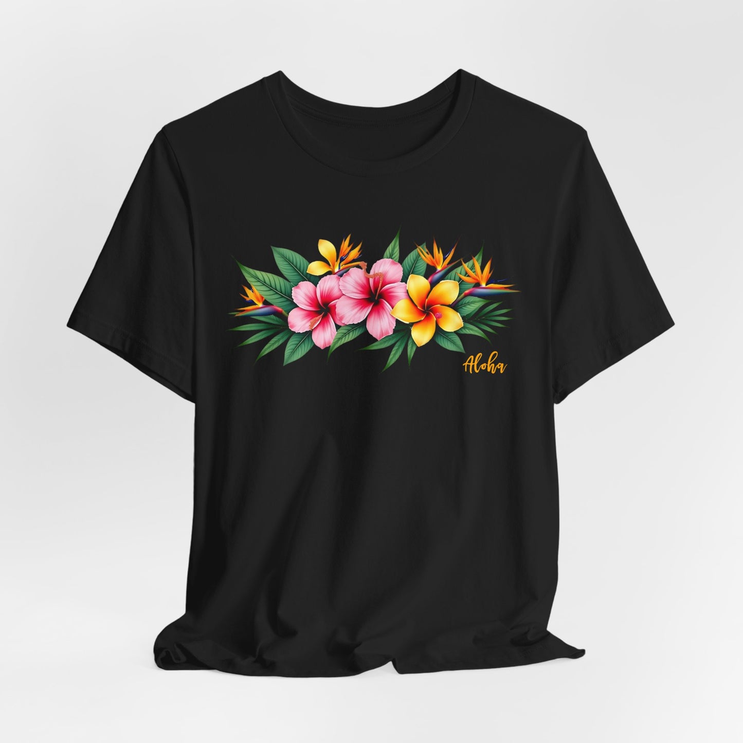 The Tropical Floral Unisex Jersey T-Shirt features a vibrant print of pink, yellow, and orange flowers with green leaves and Aloha in yellow script. Made from soft Airlume combed cotton—perfect for summer vibes!.