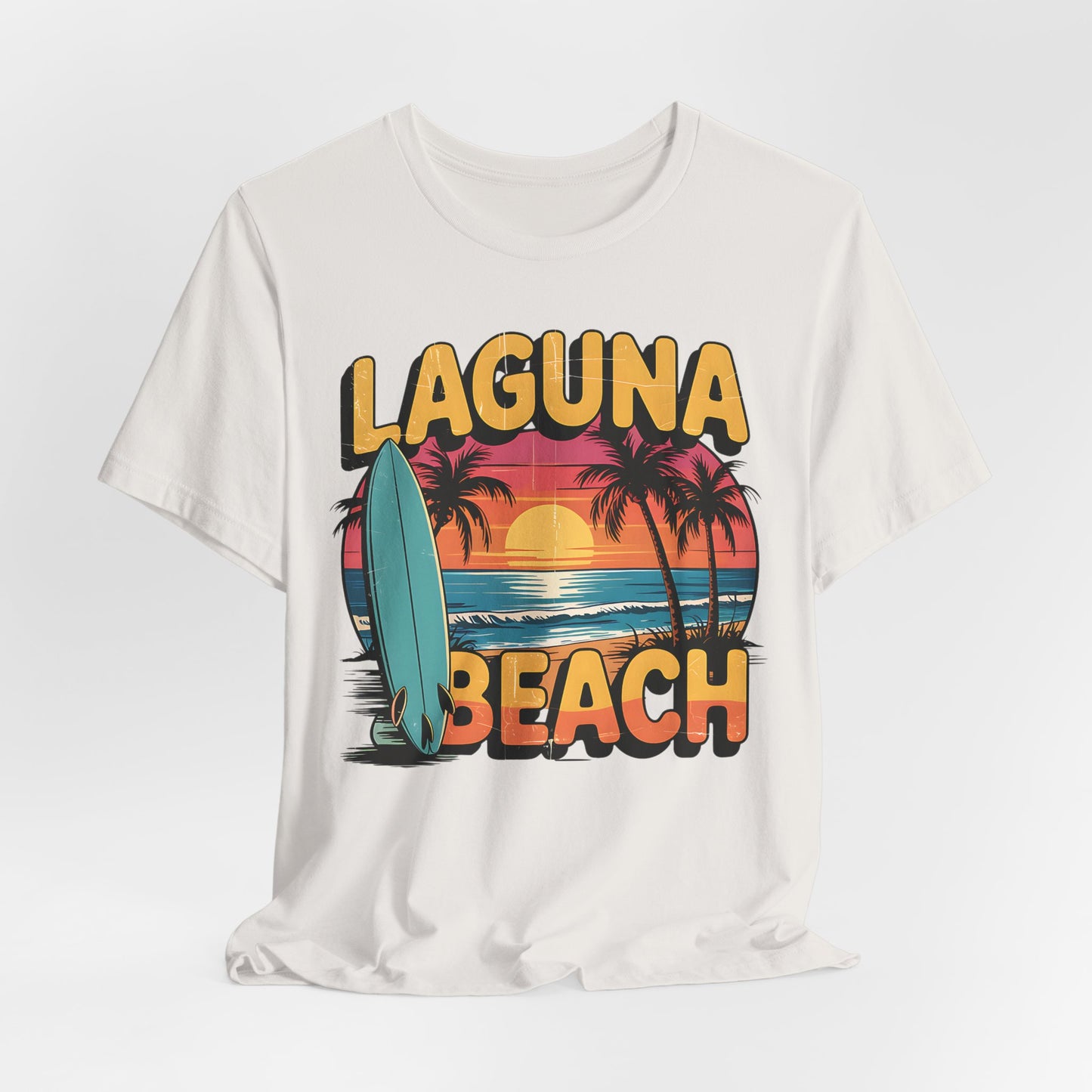 The Laguna Beach Sunset Surf Tee—Unisex Jersey Short Sleeve T-Shirt—features a vibrant sunset, palm trees, surfboard, ocean waves, and bold Laguna Beach text. Its relaxed fit makes it perfect for any beach adventure.