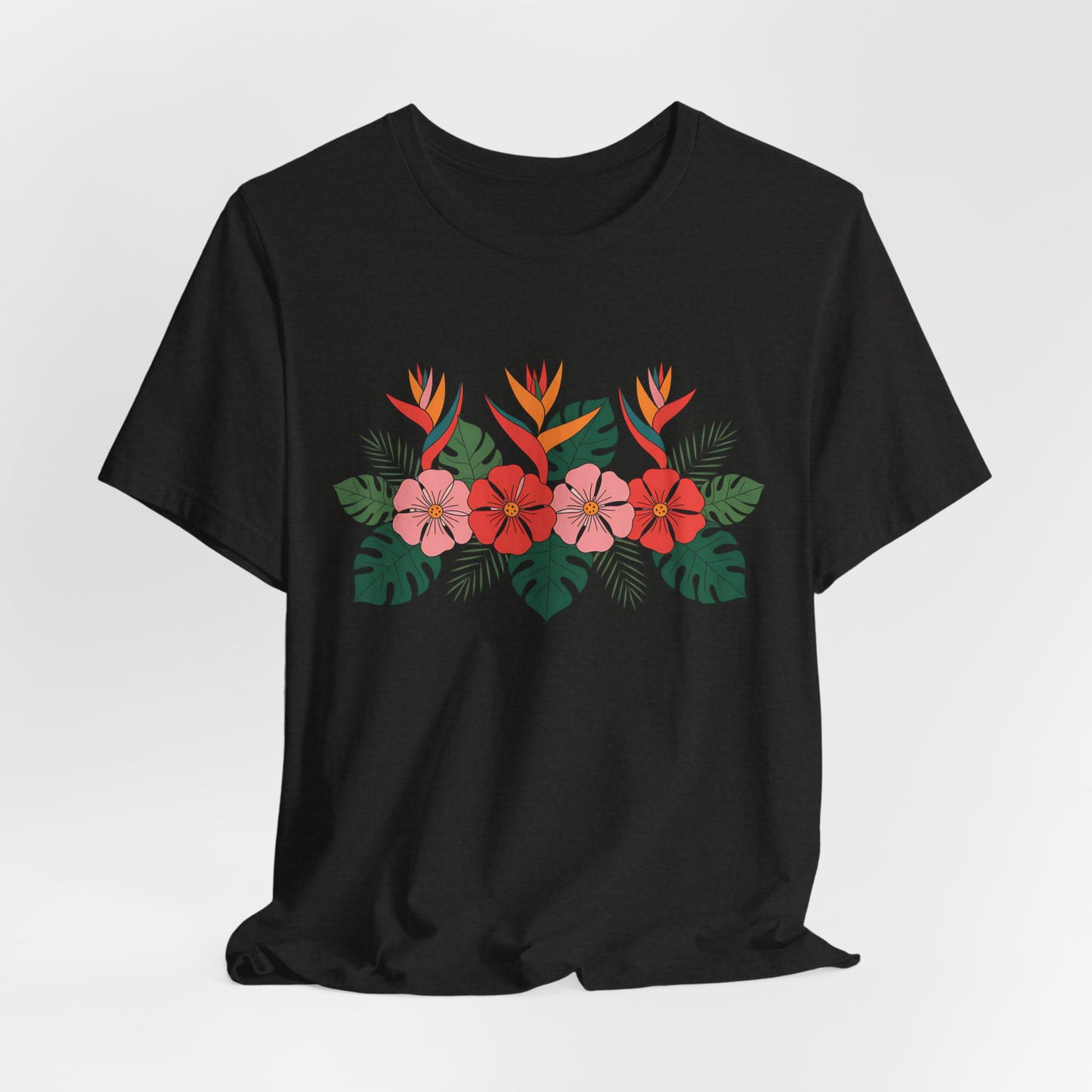 The Tropical Floral Unisex T-Shirt – Perfect for Summer Celebrations features a black base with a vivid floral print of red and pink flowers, orange bird-of-paradise, and green tropical leaves on breathable fabric.