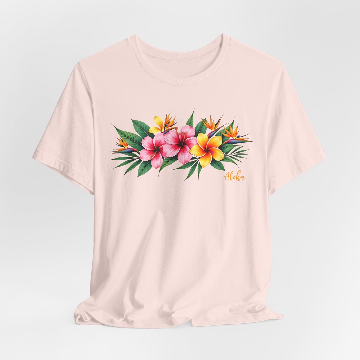 The Tropical Floral Unisex Jersey T-Shirt - Perfect for Summer Vibes features a soft Airlume cotton build, pink and yellow floral print with green leaves, and “Aloha” in orange script—ideal for adding a vibrant touch to your summer wardrobe.