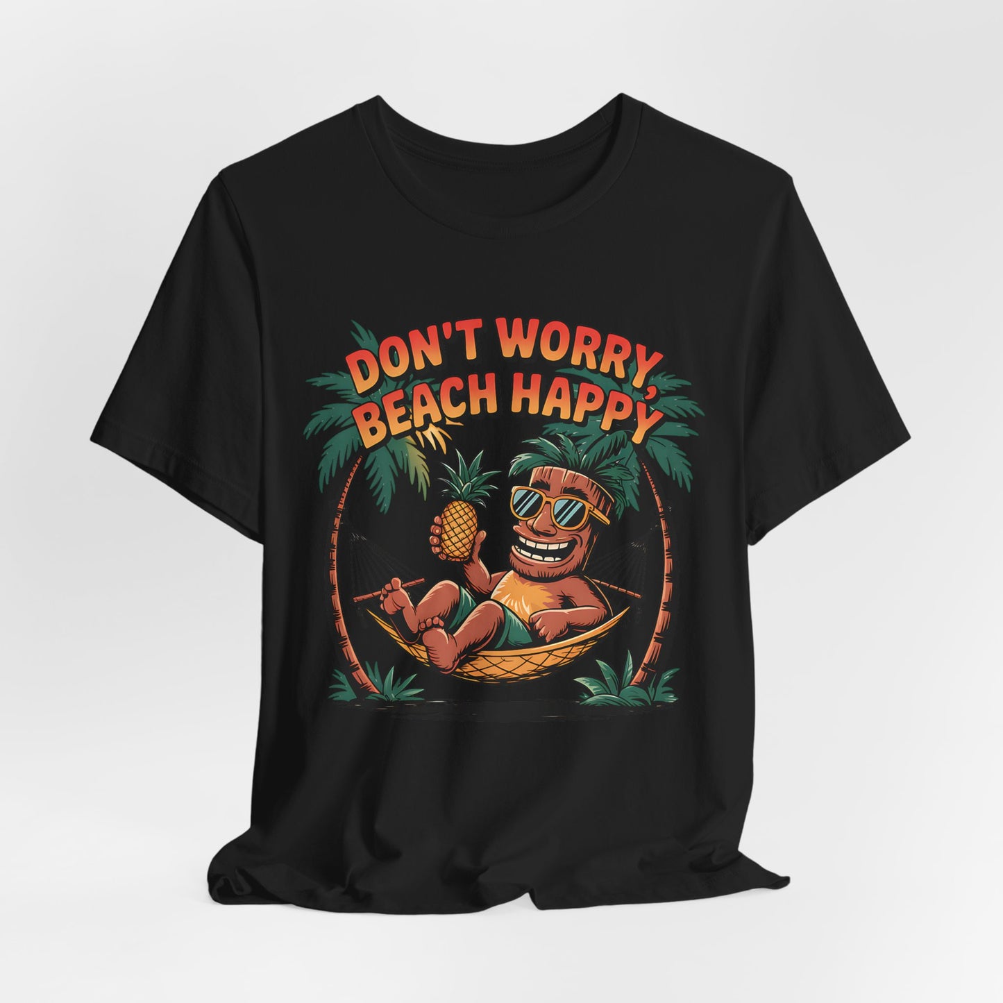 Dont Worry Beach Happy Tiki T-Shirt – a relaxed unisex jersey tee for summer vibes, featuring a cartoon character lounging in a hammock with a pineapple, sunglasses, and the slogan “DONT WORRY BEACH HAPPY”—ideal for tropical beach lovers.