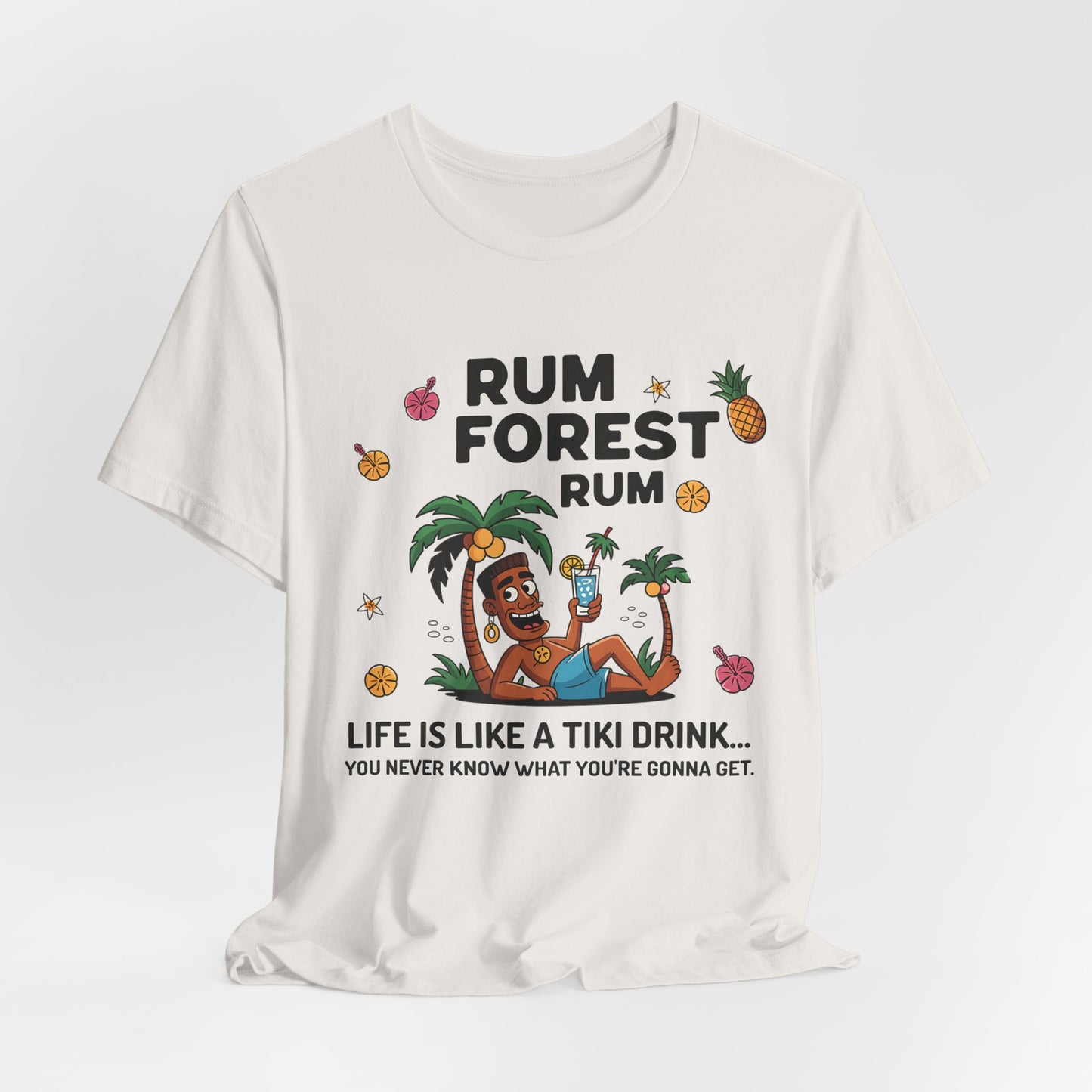 White t-shirt featuring a tiki relaxing under palm trees with a drink, pineapples, and flowers. Text reads: Life Is Like A Tiki Drink. This unisex Tiki Drink Inspired T-Shirt is a fun addition to your beach vacation apparel!.