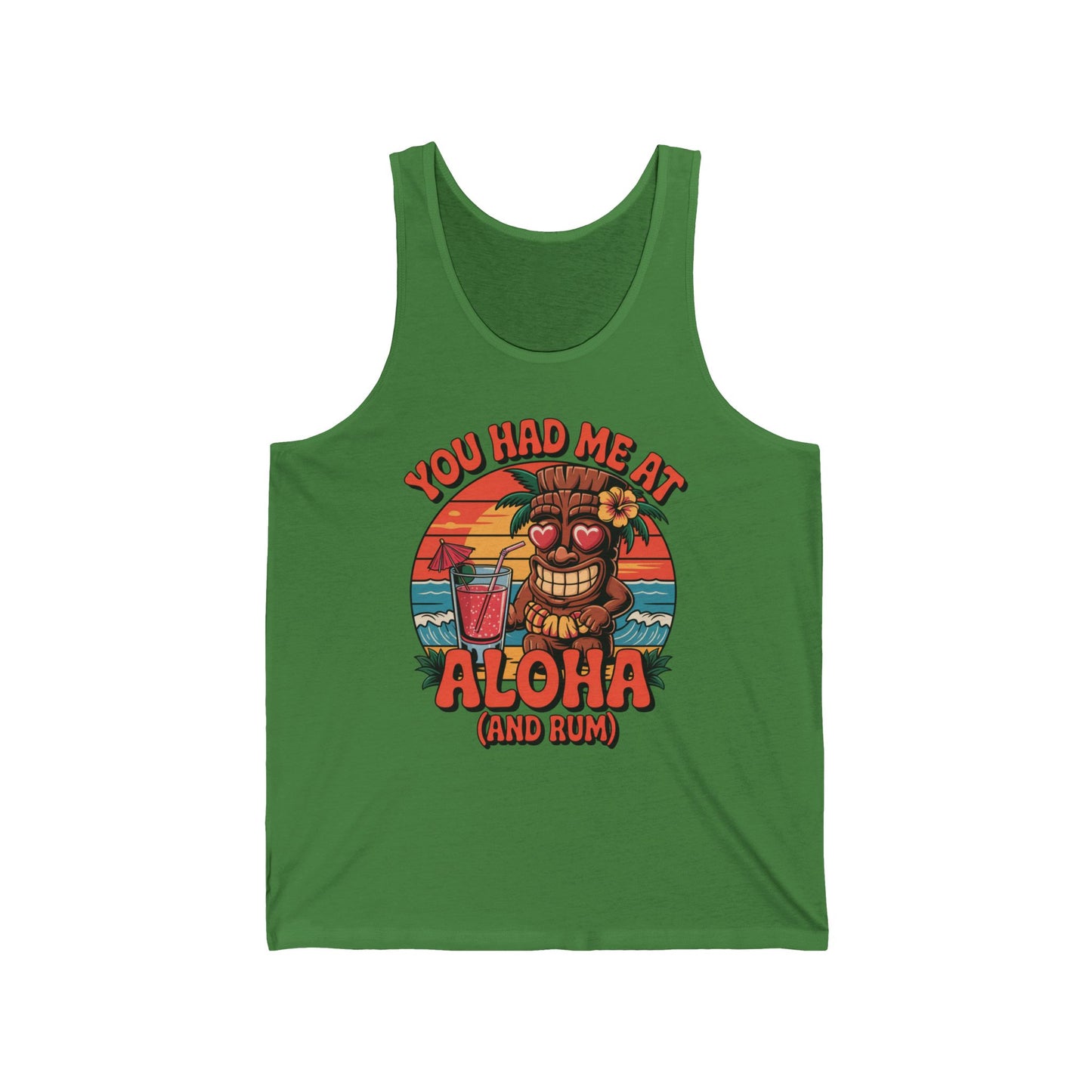 The Aloha Tiki Tank Top is a unisex jersey tank with a tropical vibe, featuring a smiling tiki with heart eyes, drink in hand, at a beach sunset. The text reads: You had me at Aloha (and rum)—ideal for beach culture lovers.