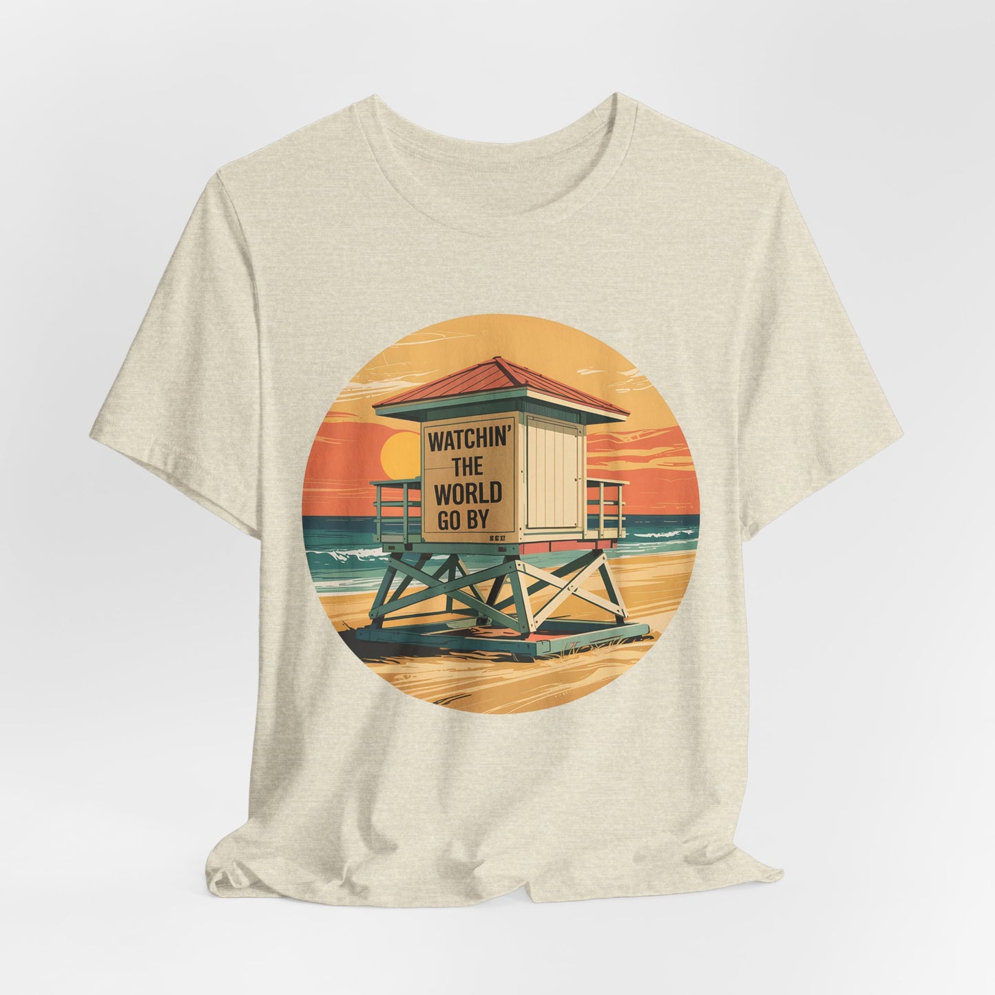 The Watchin The World Go By T-Shirt is a beige unisex jersey short sleeve shirt for beach lovers, featuring a vibrant retro-style lifeguard tower at sunset with Watchin’ the world go by on the tower.