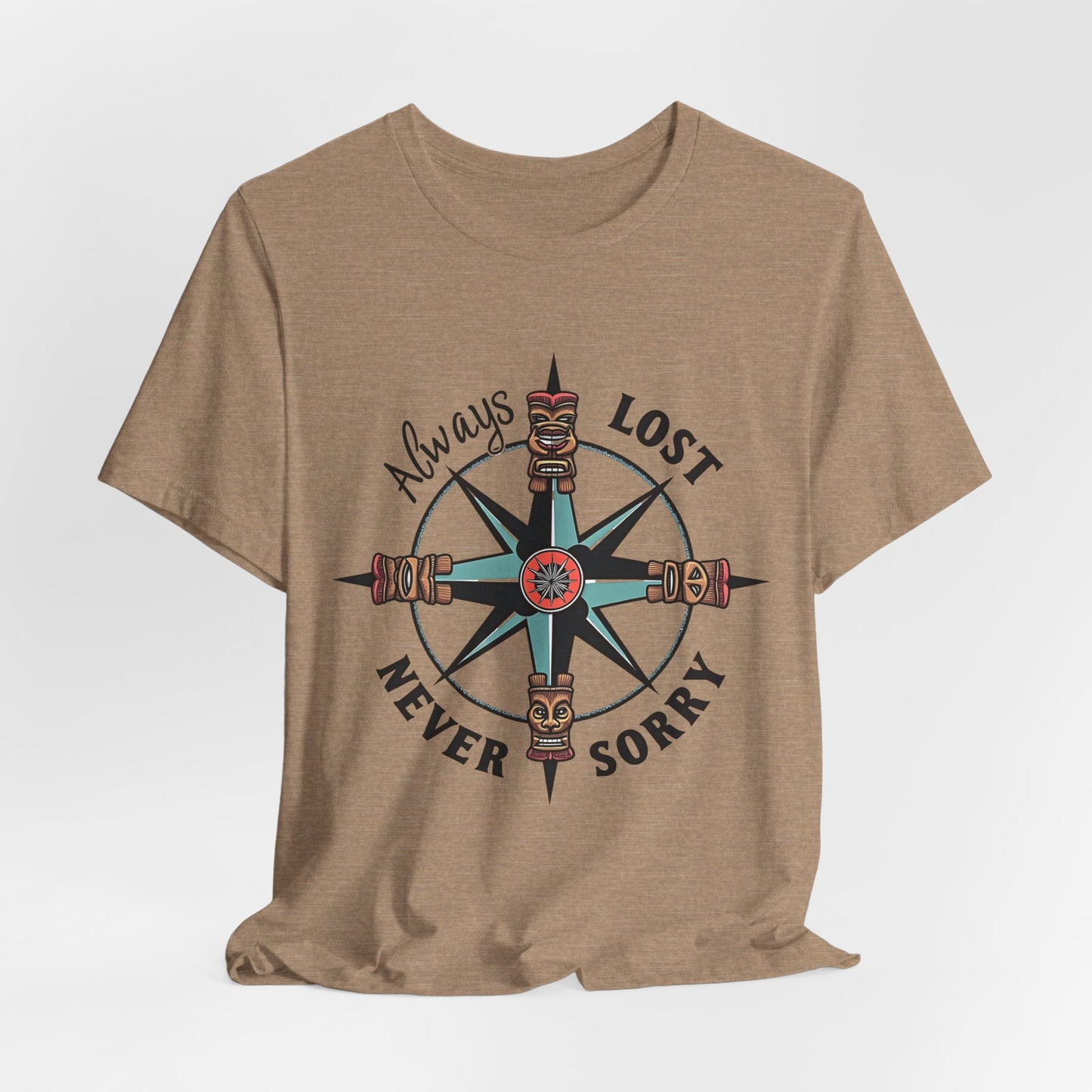 The Always Lost, Never Sorry Graphic Tee - Unisex Short Sleeve T-Shirt in tan features a compass with tiki faces and a central mask, plus the phrase Always Lost Never Sorry—ideal for adventure seekers.