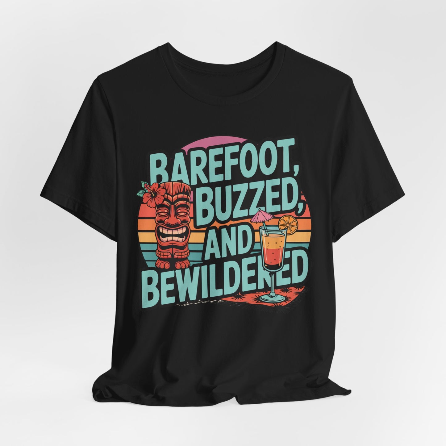 The Tropical Vibes Tiki T-Shirt features Barefoot, Buzzed, and Bewildered text, a smiling tiki statue, cocktail with orange slice, and retro sunset stripes—perfect for unisex summer celebrations.
