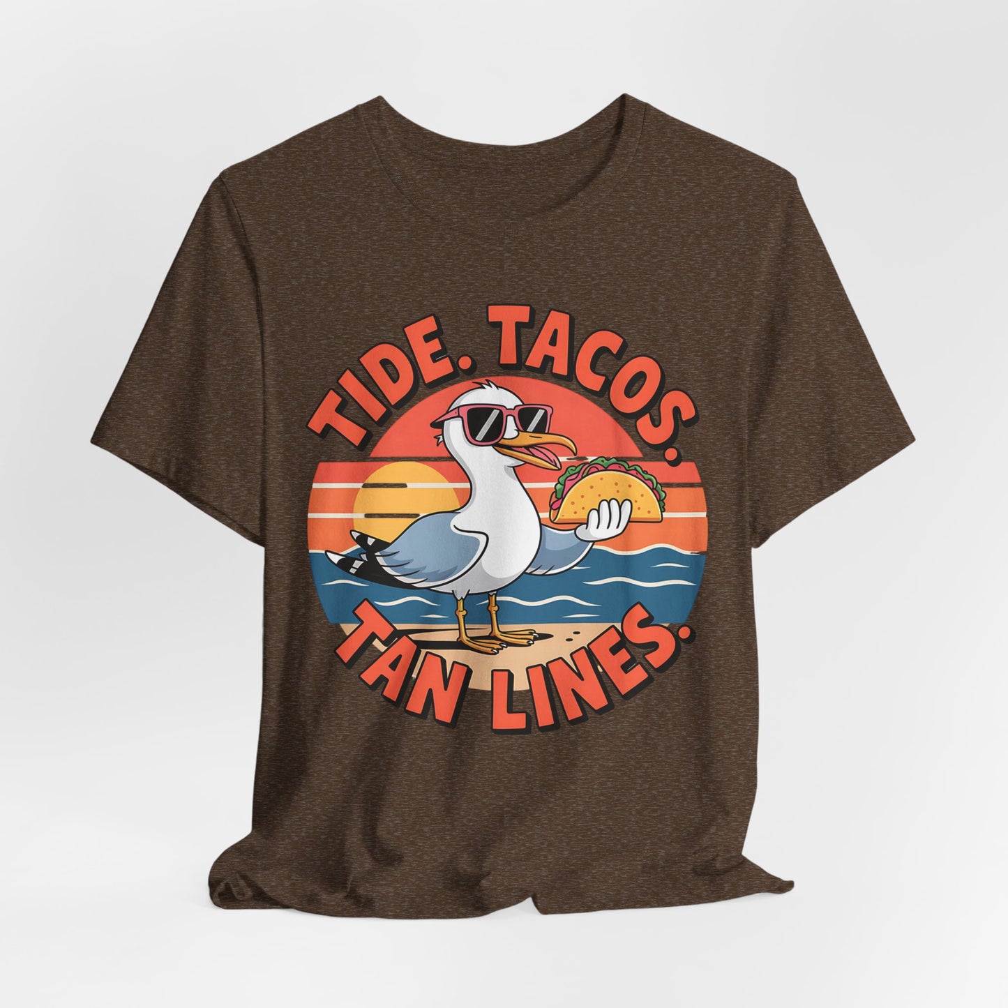 The Beach Vibes Unisex T-Shirt - Tide, Tacos, Tan Lines Summer Shirt features a cartoon seagull in sunglasses with a taco on sandy beach waves and a sunset—perfect for fun summer and beach vibes!.