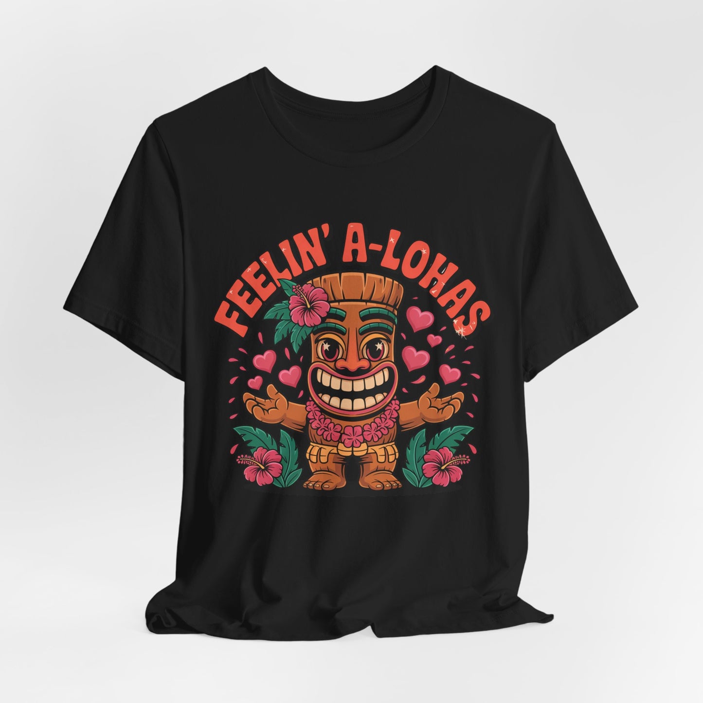 Feelin A-Lohas Unisex Jersey Tiki T-Shirt – features a colorful cartoon tiki, hearts, and hibiscus flowers with “FEELIN’ A-LOHAS” in bold orange. This fun tropical graphic shirt is perfect for casual wear.
