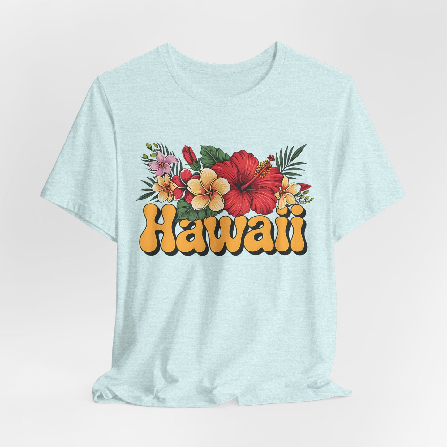 The Hawaiian Floral Unisex Tee features Hawaii in bold yellow letters with vibrant red, yellow, and pink hibiscus flowers on light blue soft Airlume cotton—perfect for beach vibes and island spirit.