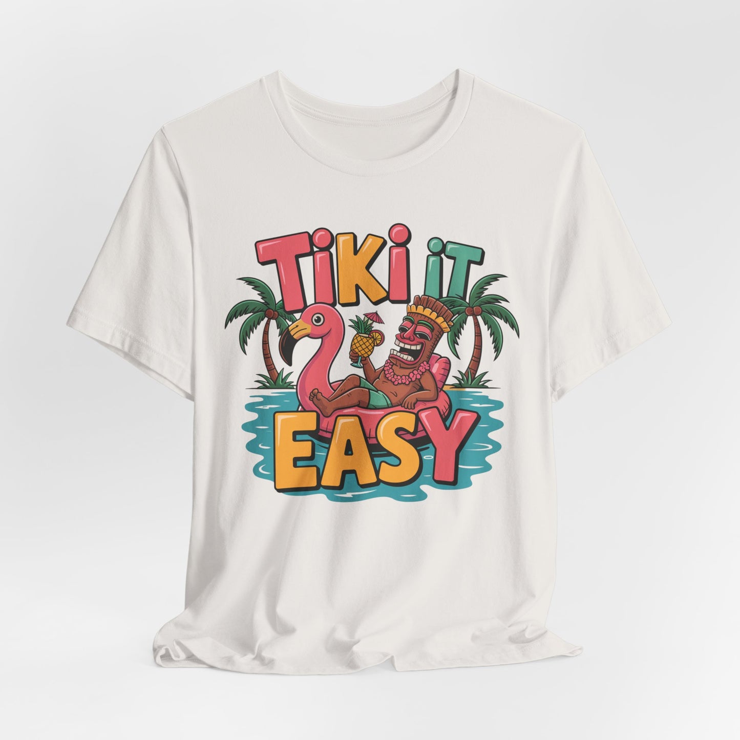 The Tiki It Easy Unisex Short Sleeve Tiki T-Shirt features a vibrant tiki figure lounging on a flamingo float with palm trees and water, plus the playful “Tiki it easy” text—a fun tropical beach vibes tee.
