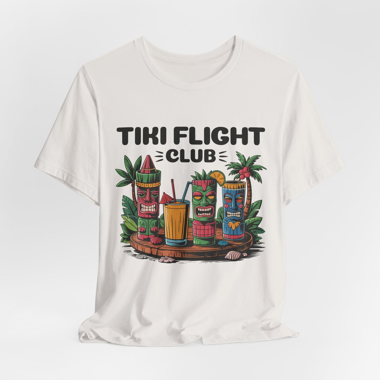 The Tiki Flight Club Graphic Tiki T-Shirt is a unisex summer vibe tee featuring three tiki statues, tropical drinks, leaves, and Tiki Flight Club lettering—ideal for casual wear or beach days.