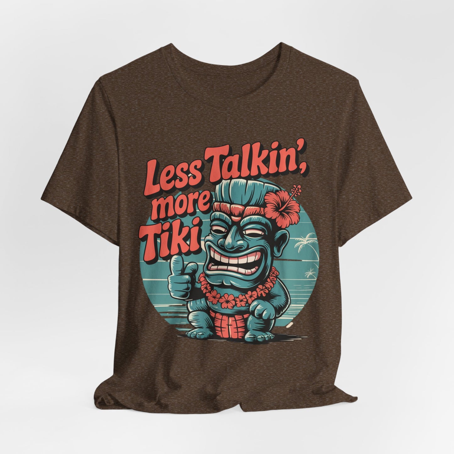 The Tiki Vibes Graphic Tiki T-Shirt - Less Talkin, More Tiki Unisex Shirt features a vibrant thumbs-up Tiki in front of a beach scene with bold red and orange text. Made from breathable fabric.