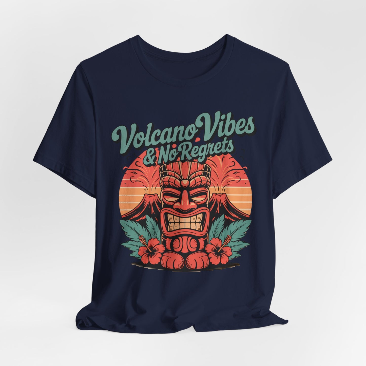 The Volcano Vibes and No Regrets Unisex Tiki T-Shirt is a navy short sleeve tee with a vibrant tiki mask, tropical leaves, hibiscus flowers, a sunset background, and bold retro “Volcano Vibes & No Regrets” text—perfect for summer adventures!.
