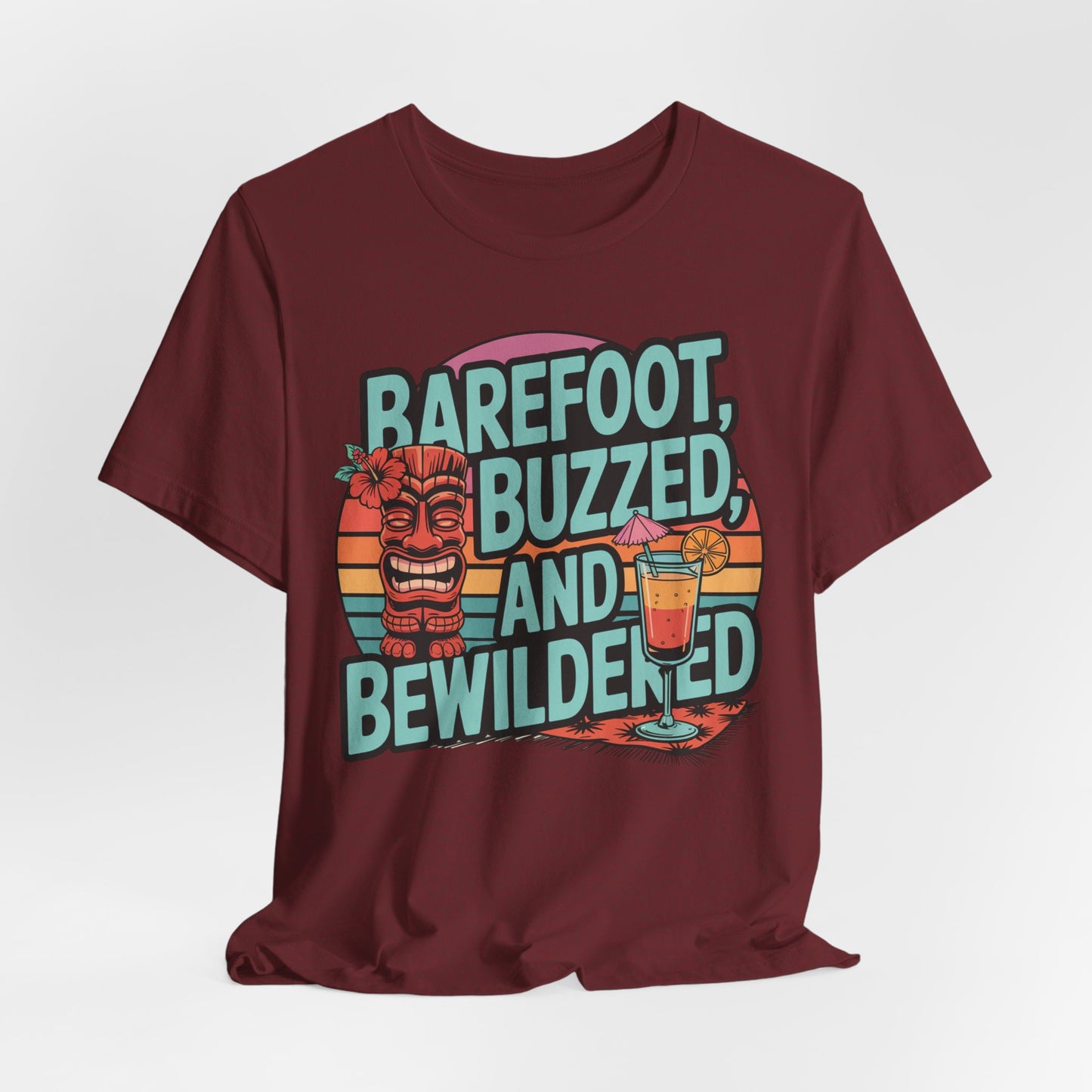 The Tropical Vibes Tiki T-Shirt - Barefoot, Buzzed, and Bewildered features a lively design with a tiki statue, tropical drink, and sunset backdrop—ideal for adding fun summer vibes to any celebration.
