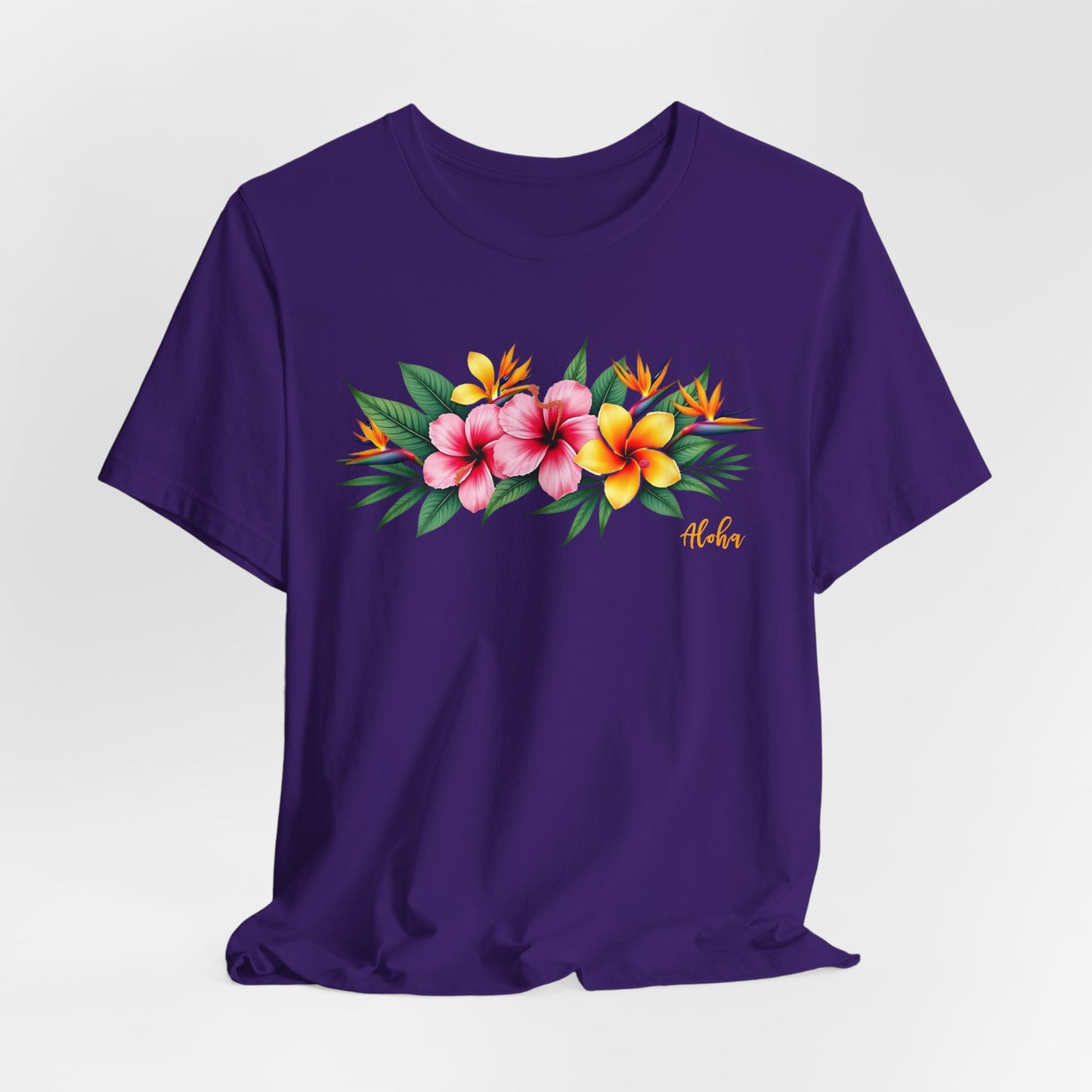 The Tropical Floral Unisex Jersey T-Shirt - Perfect for Summer Vibes features a vibrant purple design with colorful tropical flowers, green leaves, and Aloha in yellow script. Made from soft Airlume combed cotton for all-day comfort.