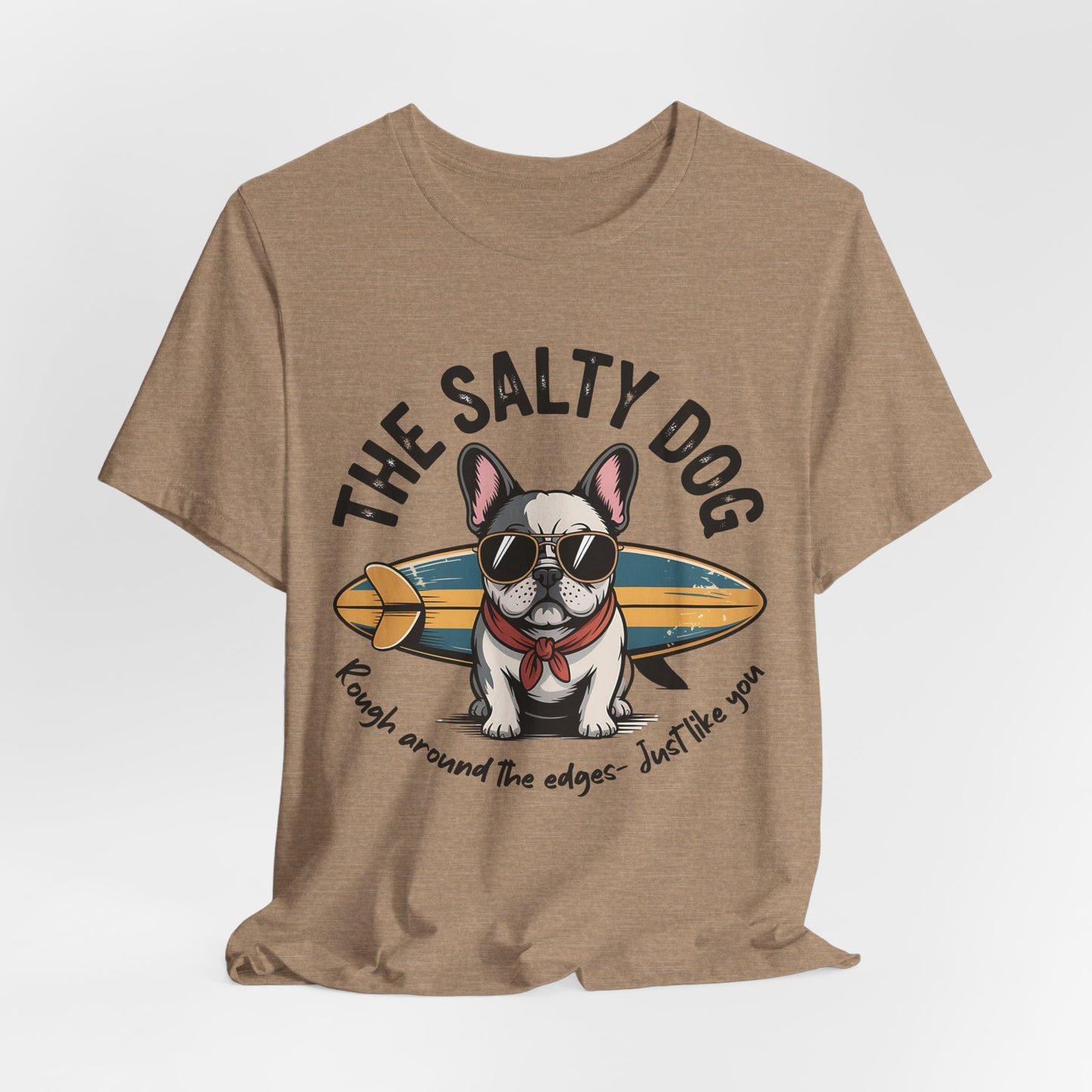 The Salty Dog Unisex Surf T-Shirt: Tan tee with a French Bulldog in sunglasses and scarf, plus surfboard. Features THE SALTY DOG and Rough around the edges – Just like you. Perfect for beach outings.