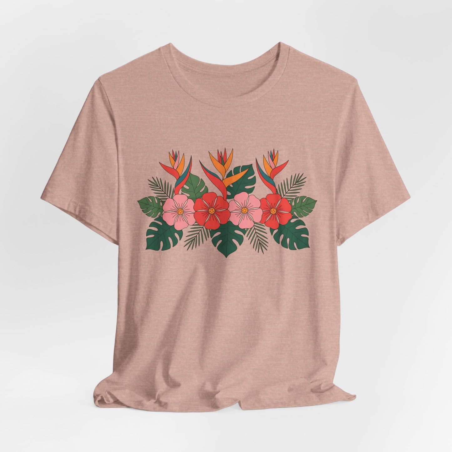 The Tropical Floral Unisex T-Shirt – Perfect for Summer Celebrations showcases a vibrant floral print with hibiscus, bird of paradise blooms, palm, and monstera leaves on light brown breathable fabric for all-day comfort.