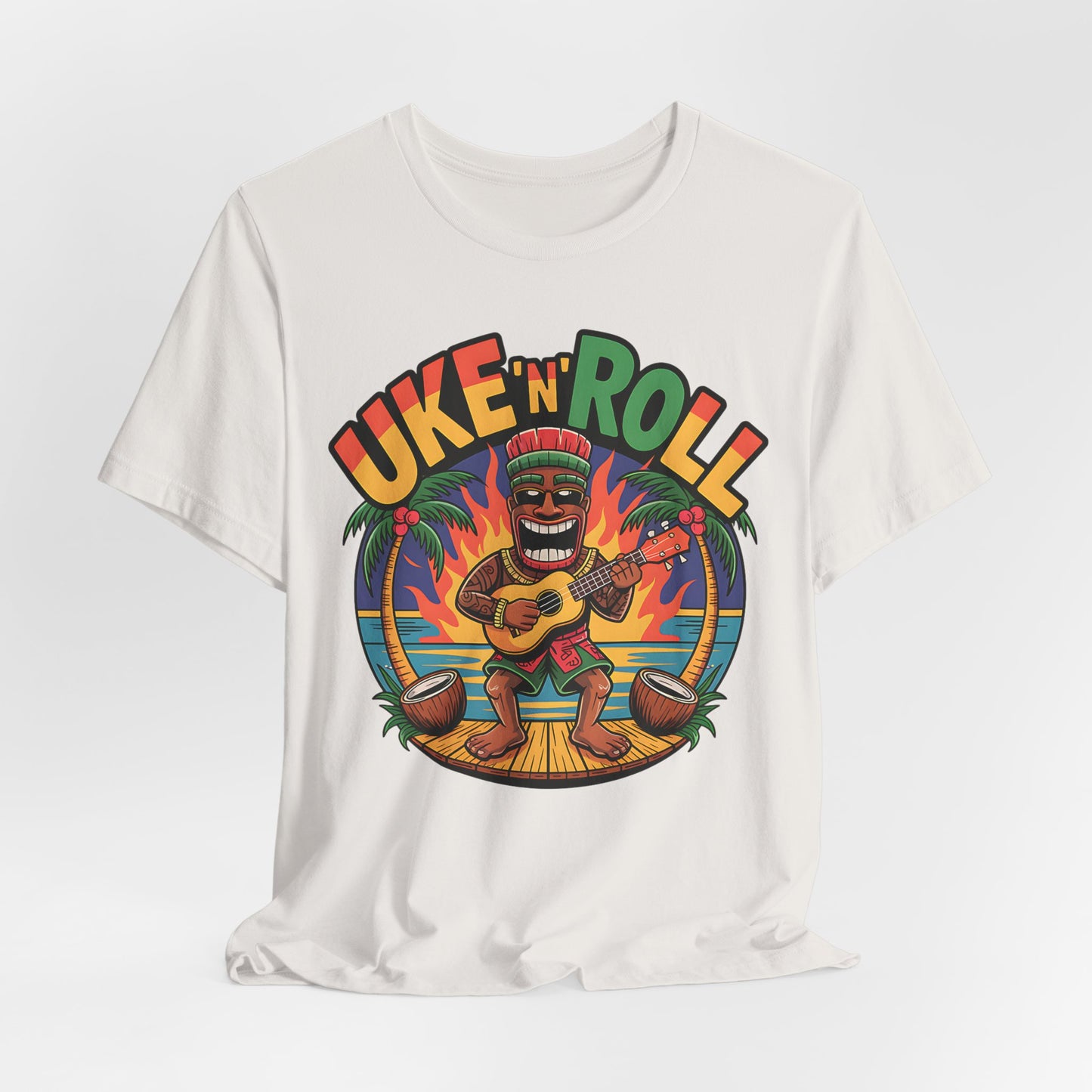 The Uke n Roll Unisex Jersey Tiki T-Shirt features a vibrant cartoon tiki playing ukulele at sunset—ideal for music lovers and beach fans seeking fun vibes.
