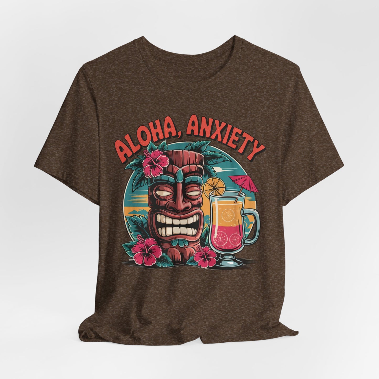The Aloha Anxiety Unisex Short Sleeve Tiki T-Shirt features a colorful tiki mask, hibiscus flowers, tropical drink with pink umbrella, and bold red “Aloha Anxiety” text—crafted from soft Airlume cotton for all-day comfort.