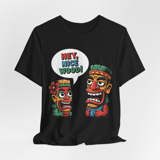 The Tropical Humor Short Sleeve Tiki T-Shirt - Hey, Nice Wood! Graphic is a black unisex tee with two colorful cartoon tiki heads; one has a flower, the other smiles and says HEY, NICE WOOD! in bright colors.