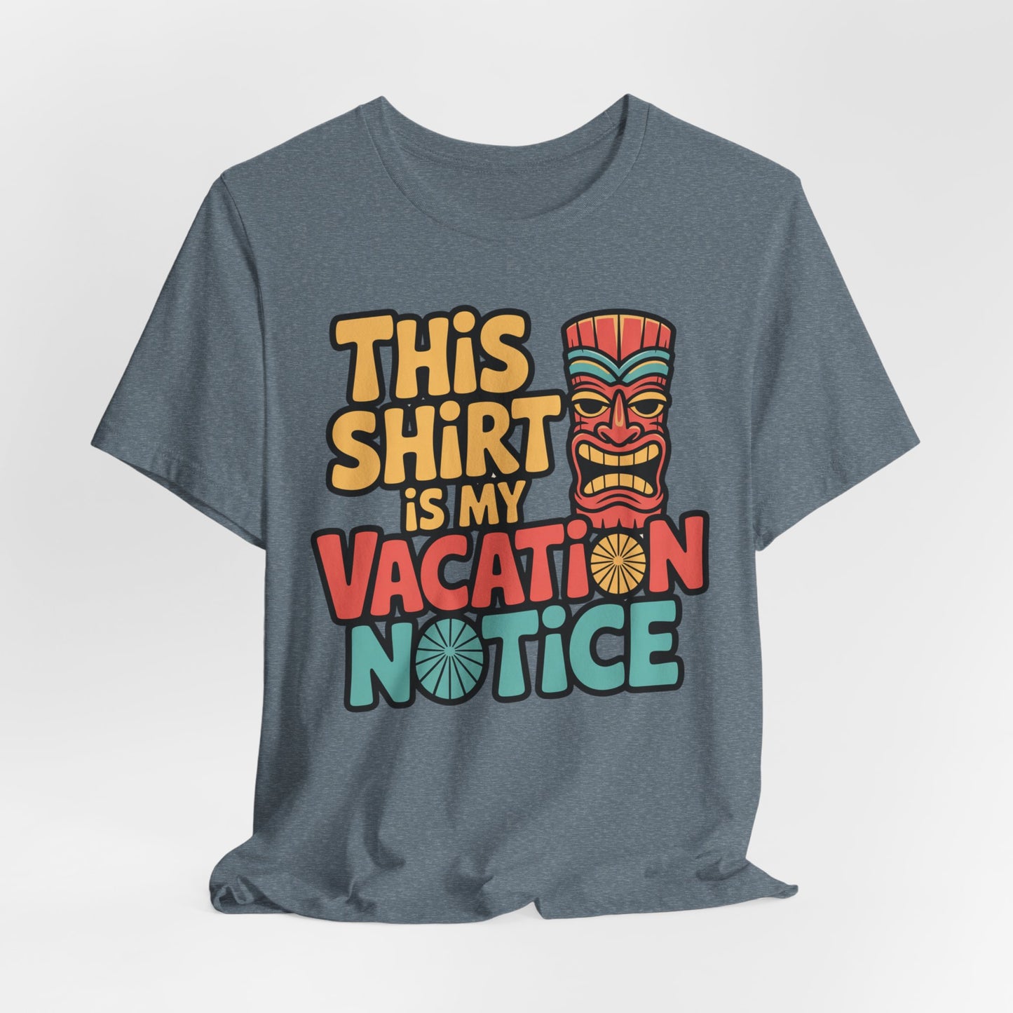 The Tiki T-Shirt - This Shirt is My Vacation Notice Funny Travel T-Shirt is a gray unisex jersey featuring colorful yellow, red, and teal vacation-inspired text beside a stylized tiki mask.