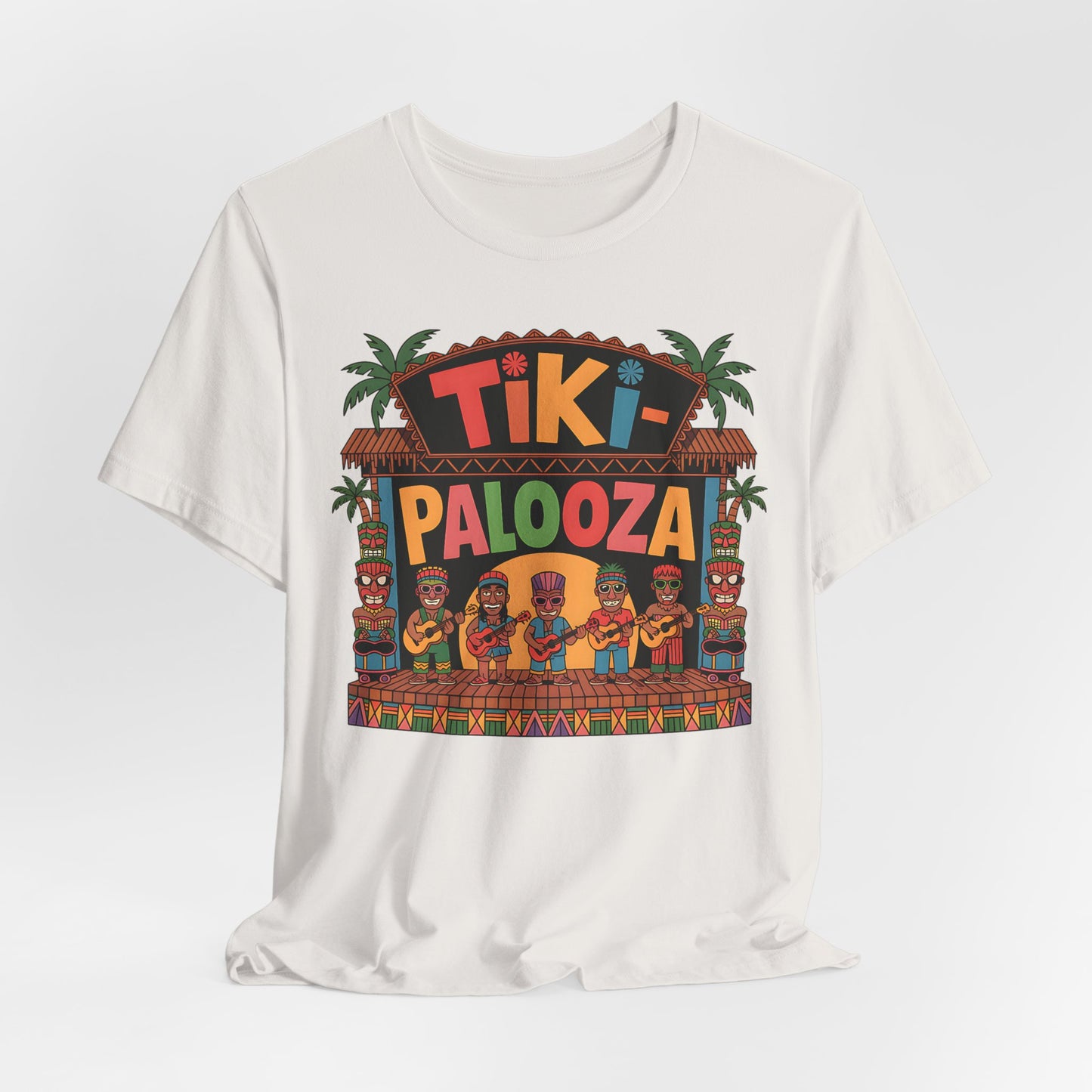 The Tiki Palooza Unisex Jersey Tiki T-Shirt features a festive floral graphic with a tiki hut stage, cartoon hula dancers, tiki statues, palm trees, and vibrant multicolored text—perfect for tropical celebrations or summer parties.